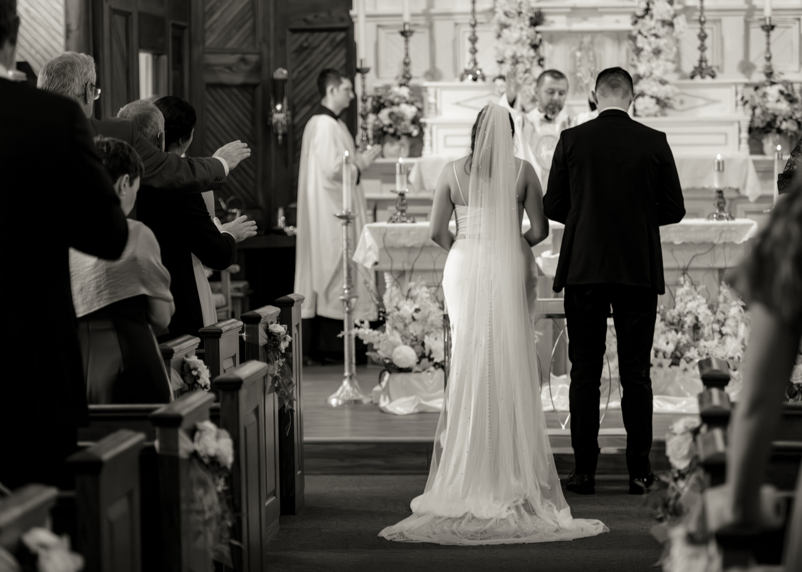 a catholic bride and groom receive a blessing from their wedding guests during their catholic wedding mass at st. ambrose Catholic church in st. augustine floriida