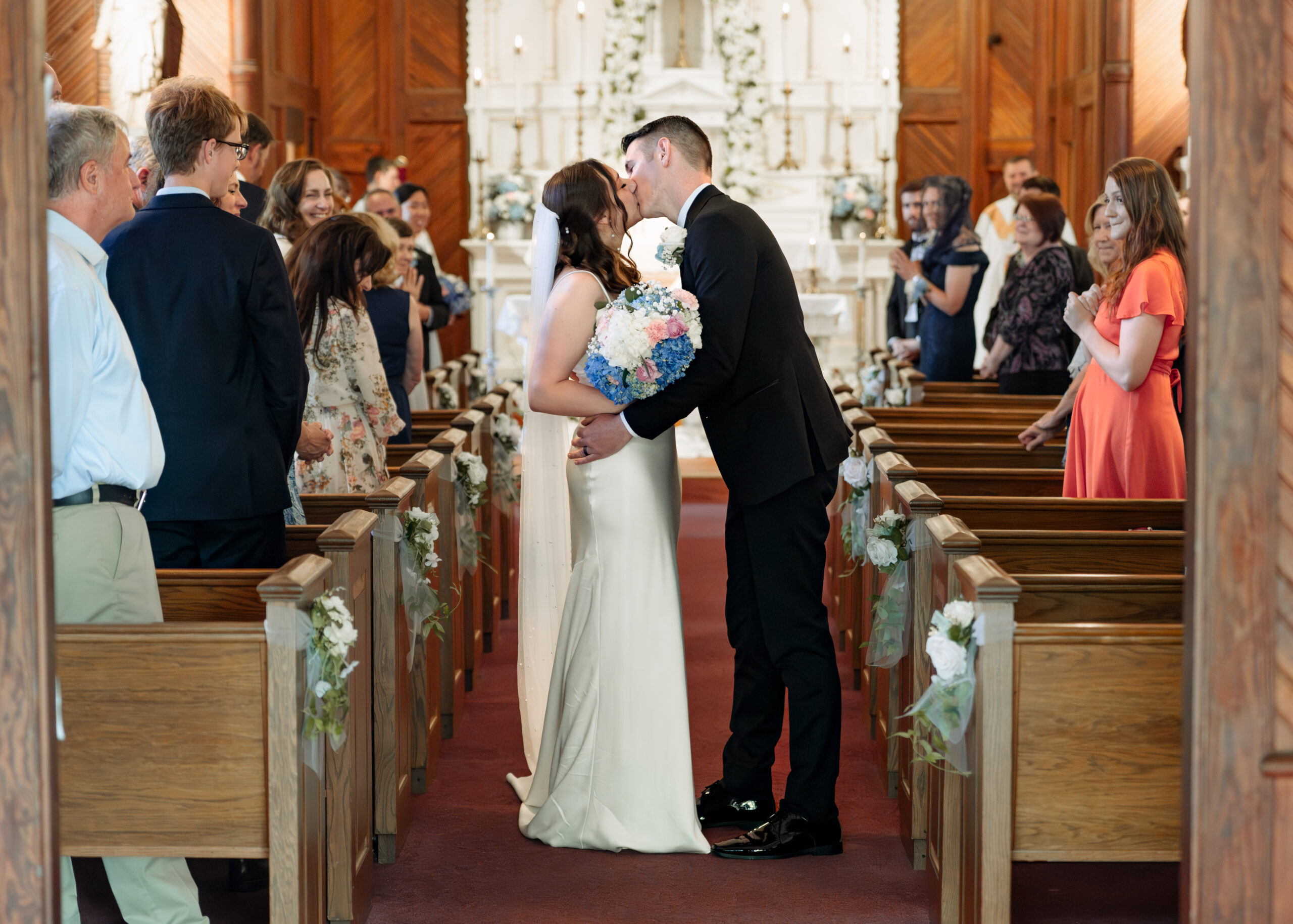 a catholic bride and groom share a kiss at the end of their catholic wedding mass at st. ambrose Catholic church in st. augustine florida