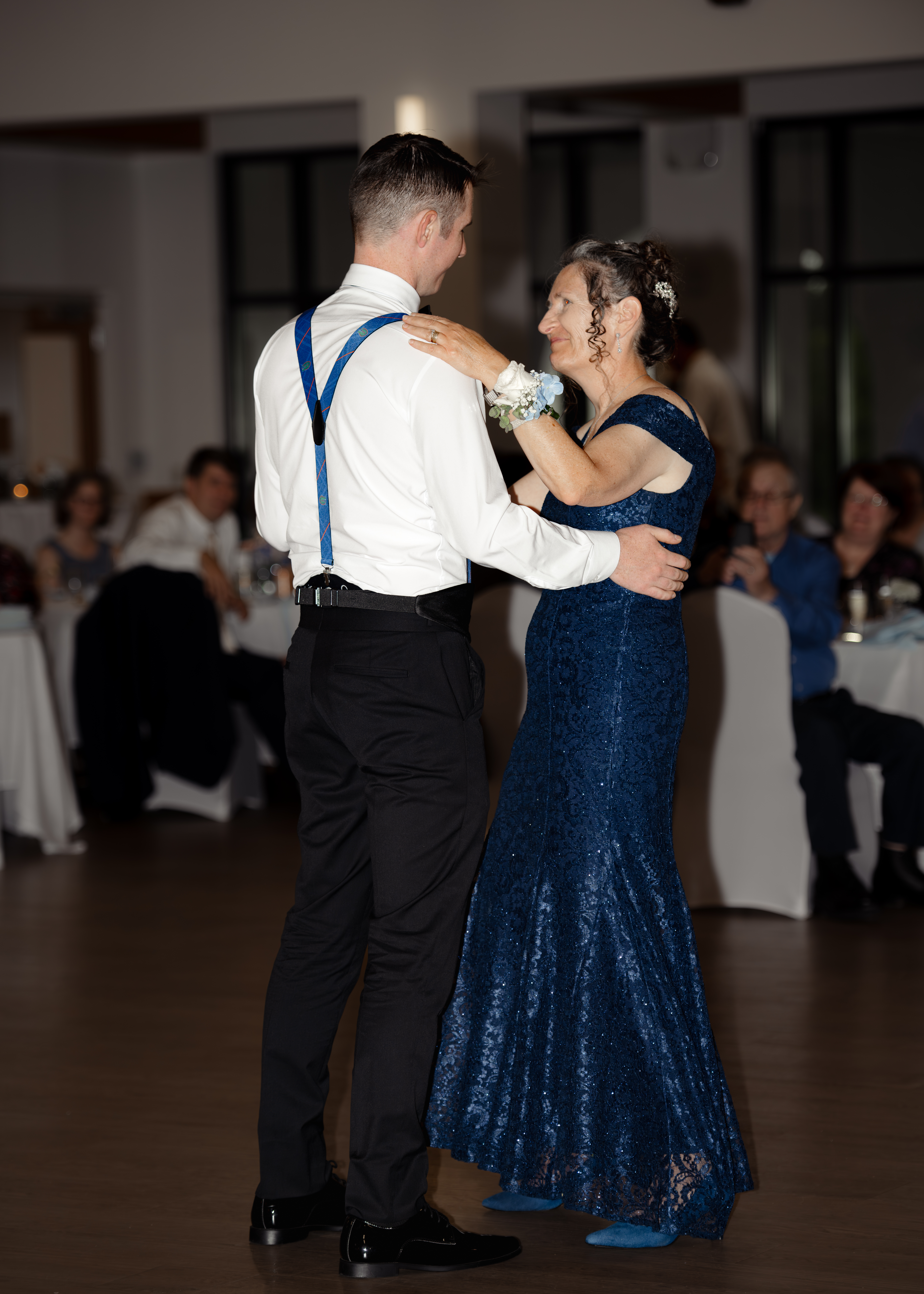 Groom shares a heartfelt mother-son dance at his Catholic wedding reception in St. Augustine at St. Anastasia Church. The groom’s mother wears a stunning navy blue gown while guests look on emotionally.