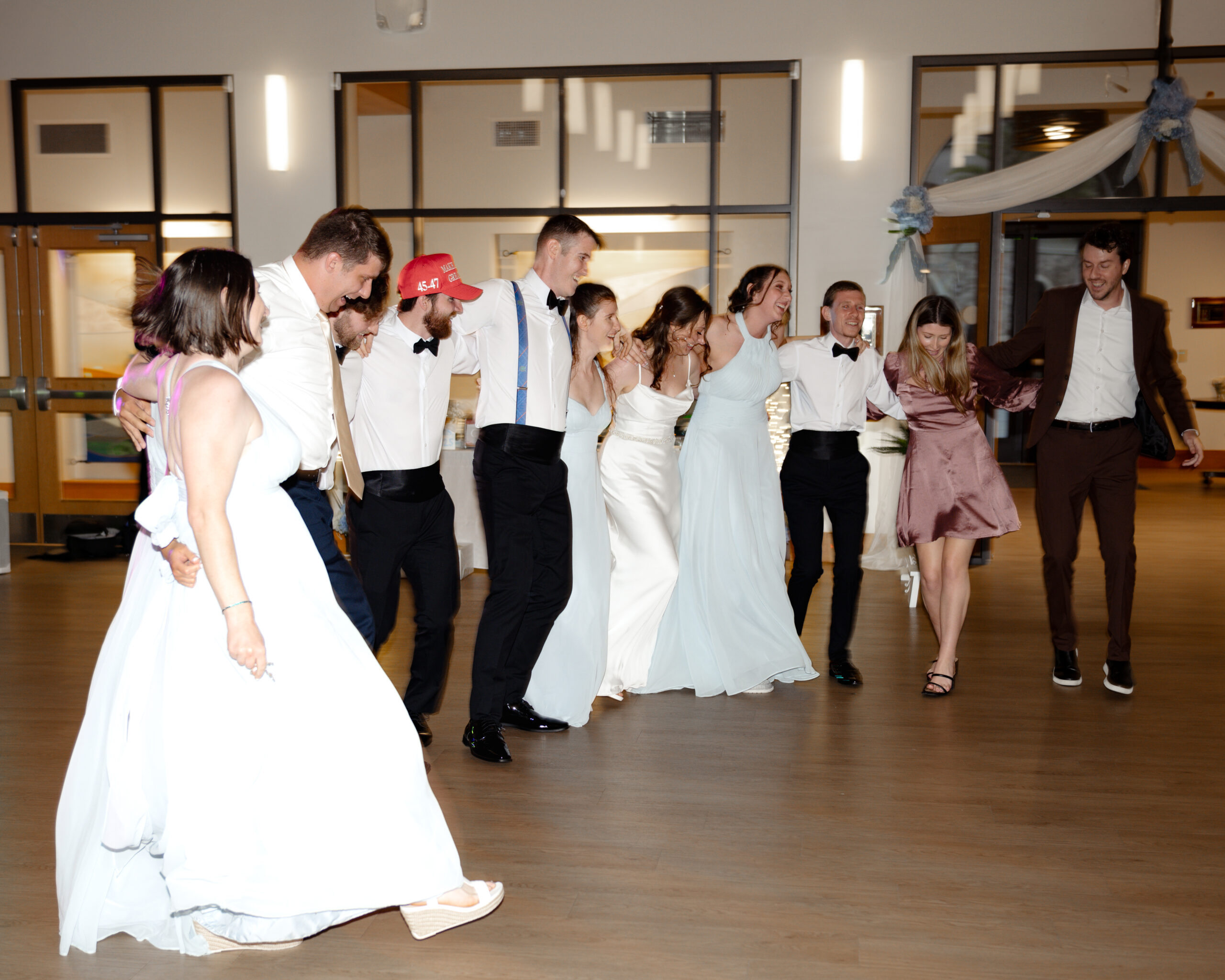 Joyful bride, groom, and wedding party dance in a circle during a fun Catholic wedding celebration at St. Anastasia Catholic Church in St. Augustine, Florida.