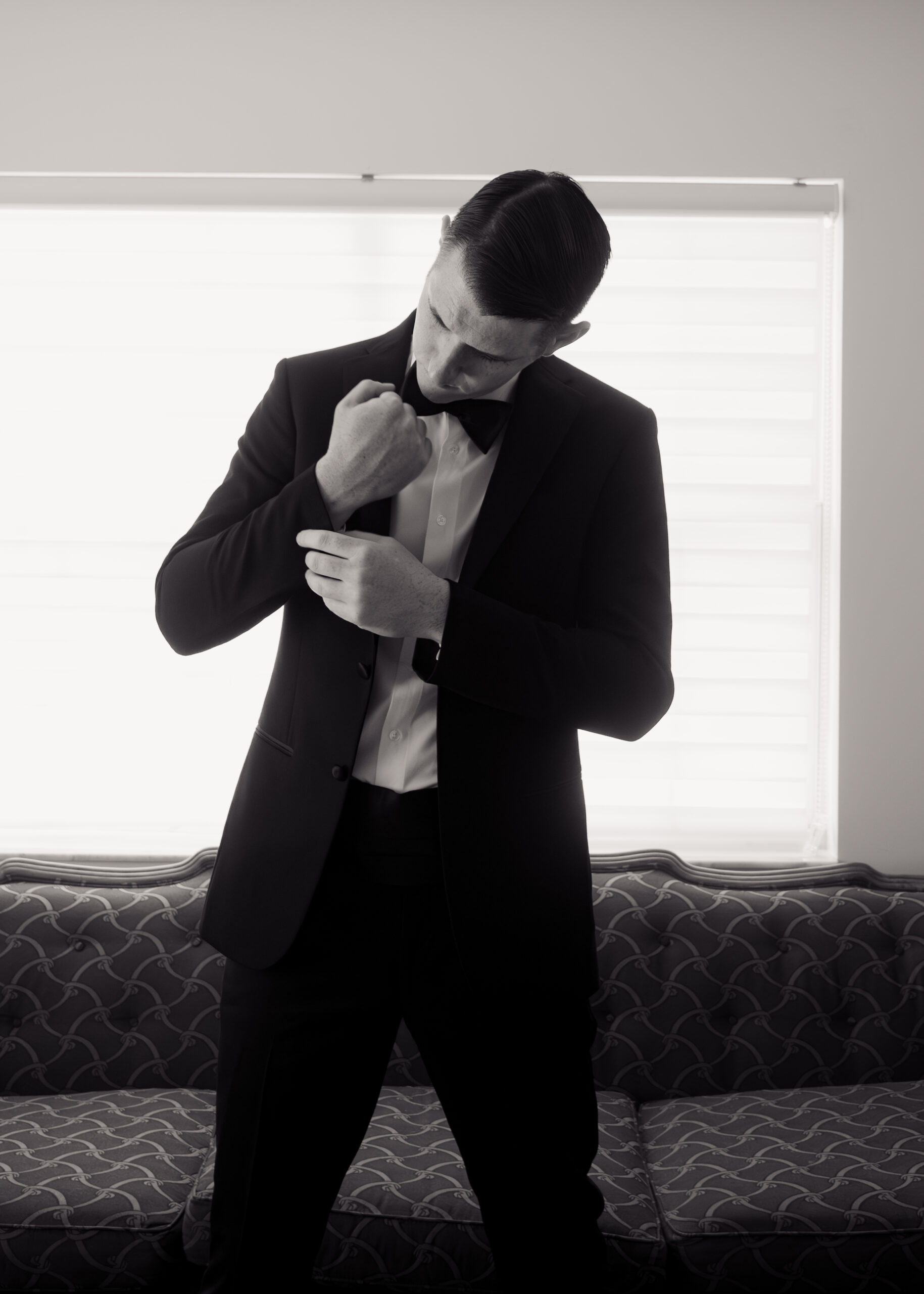 A black-and-white image of the groom adjusting his cufflinks while getting ready for his Catholic wedding in St. Augustine, Florida. This stylish shot highlights his meticulous preparations, adding an elegant touch to the wedding day atmosphere.