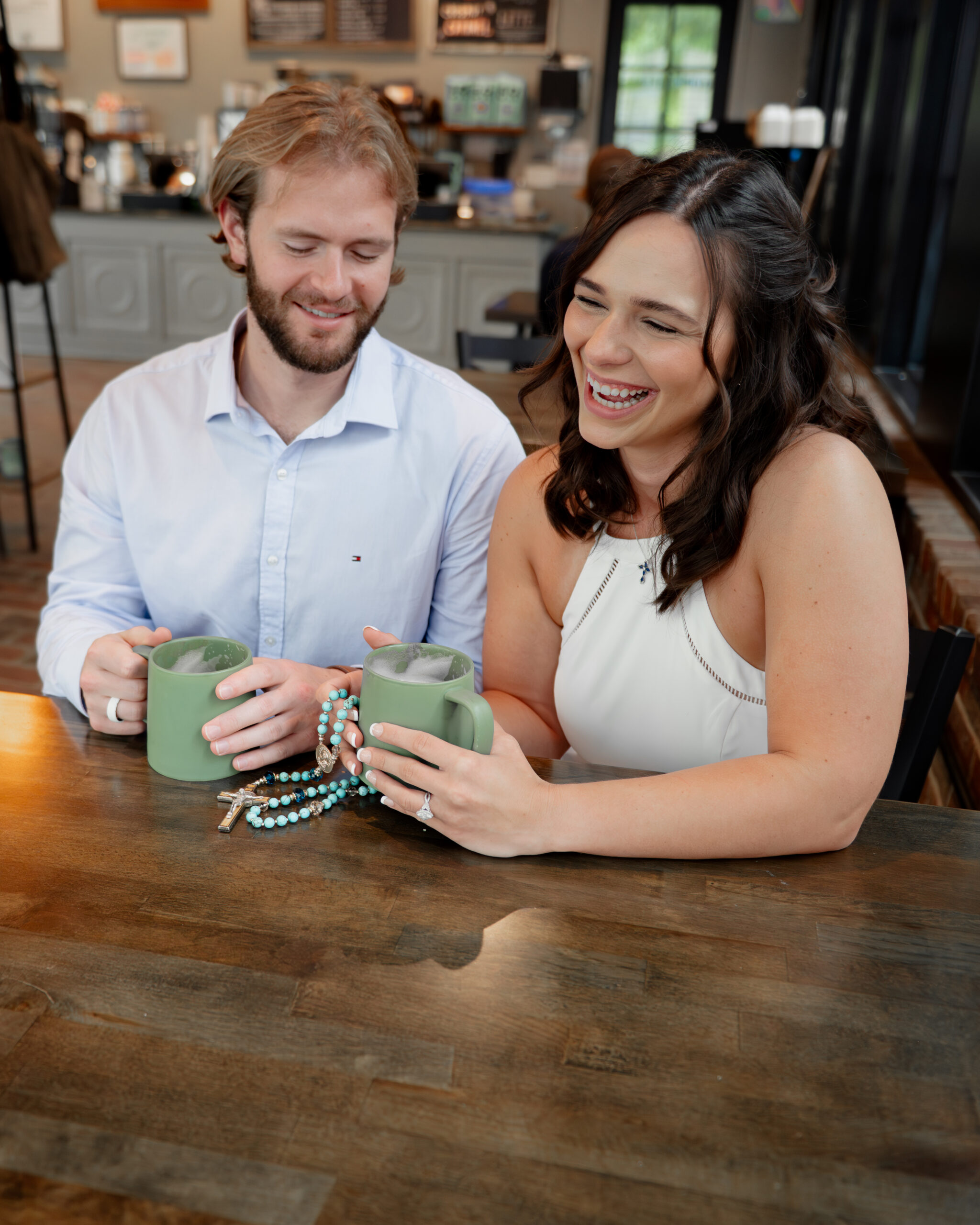 A catholic couple laughs and shares authentic joy during their coffee house engagement session