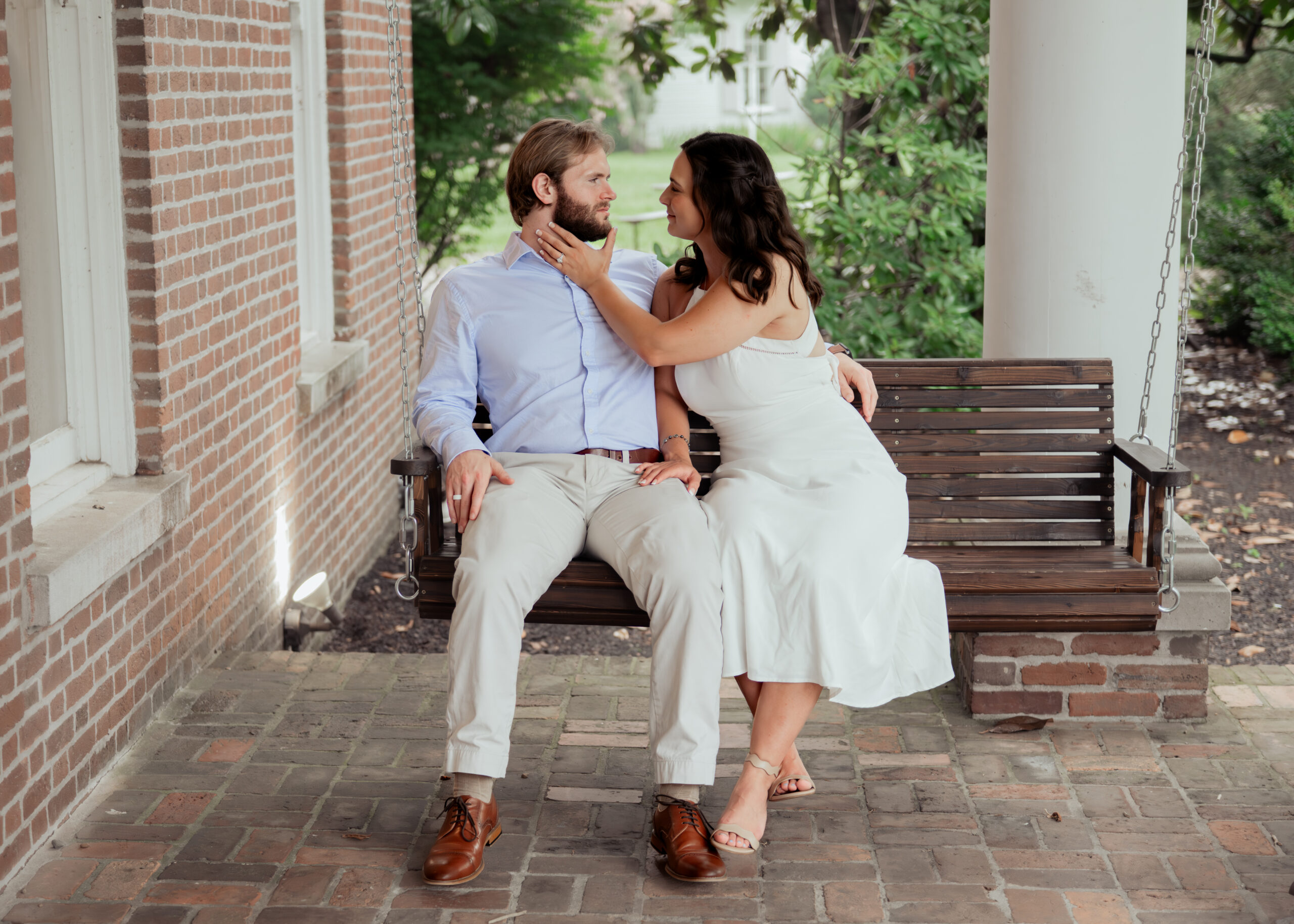 A catholic couple shares a sweet moment on the porch swing of a historic tennessee mansion during their tender summer engagement session