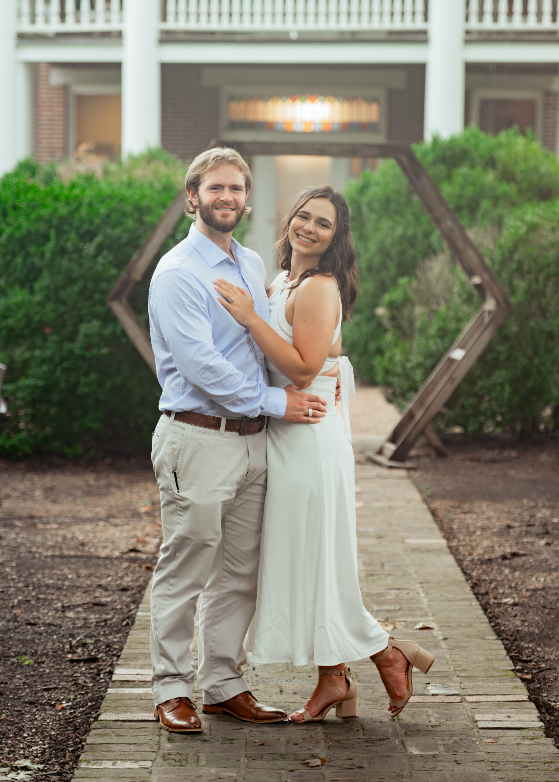 a relaxed and hazy portrait of a catholic couple smiling at the camera shows the summer heat and relaxed nature of this tn engagement session