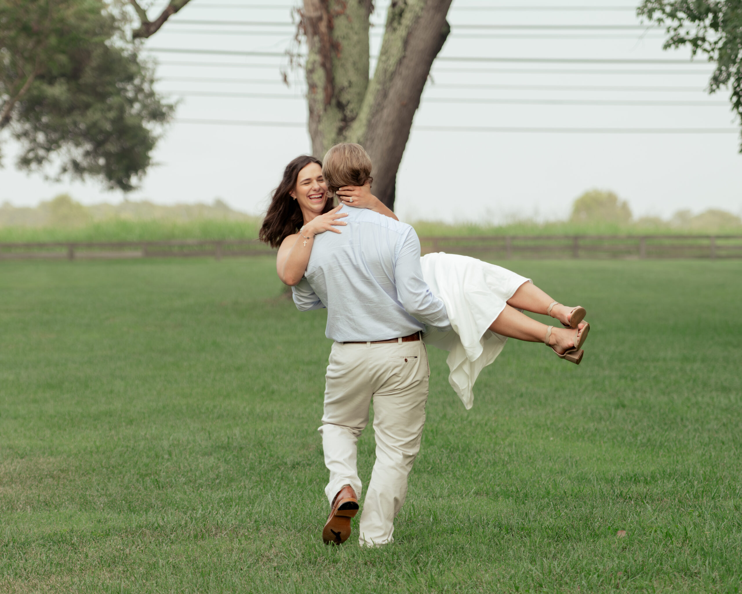 A man swings his bride around in a dreamy tennessee field during their catholic thompson's station engagement session.