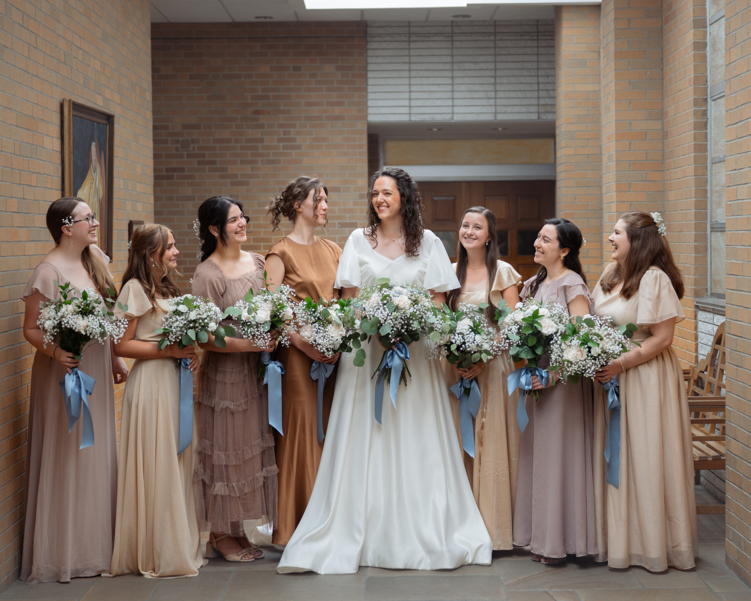 A catholic bride laughs while standing with her supportive and loving bridesmaids ahead of her wedding in huntsville, al