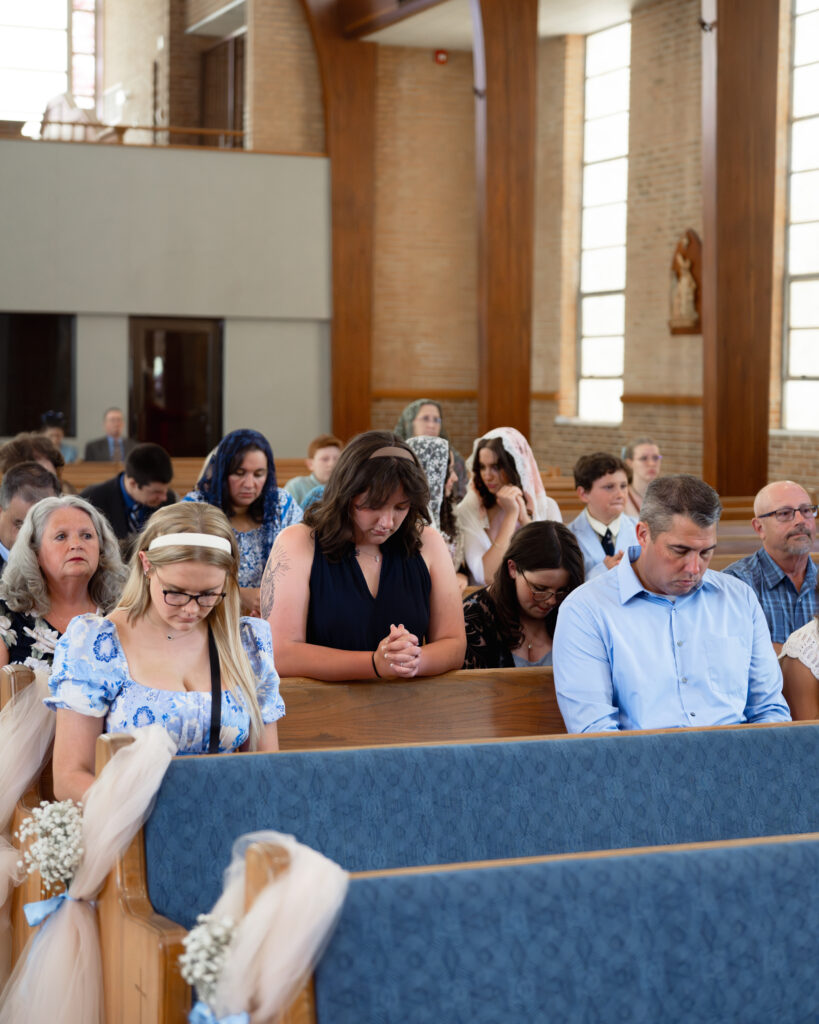 wedding guests intentionally pray for a catholic couple ahead of their wedding mass at holy spirit catholic church in huntsville, al