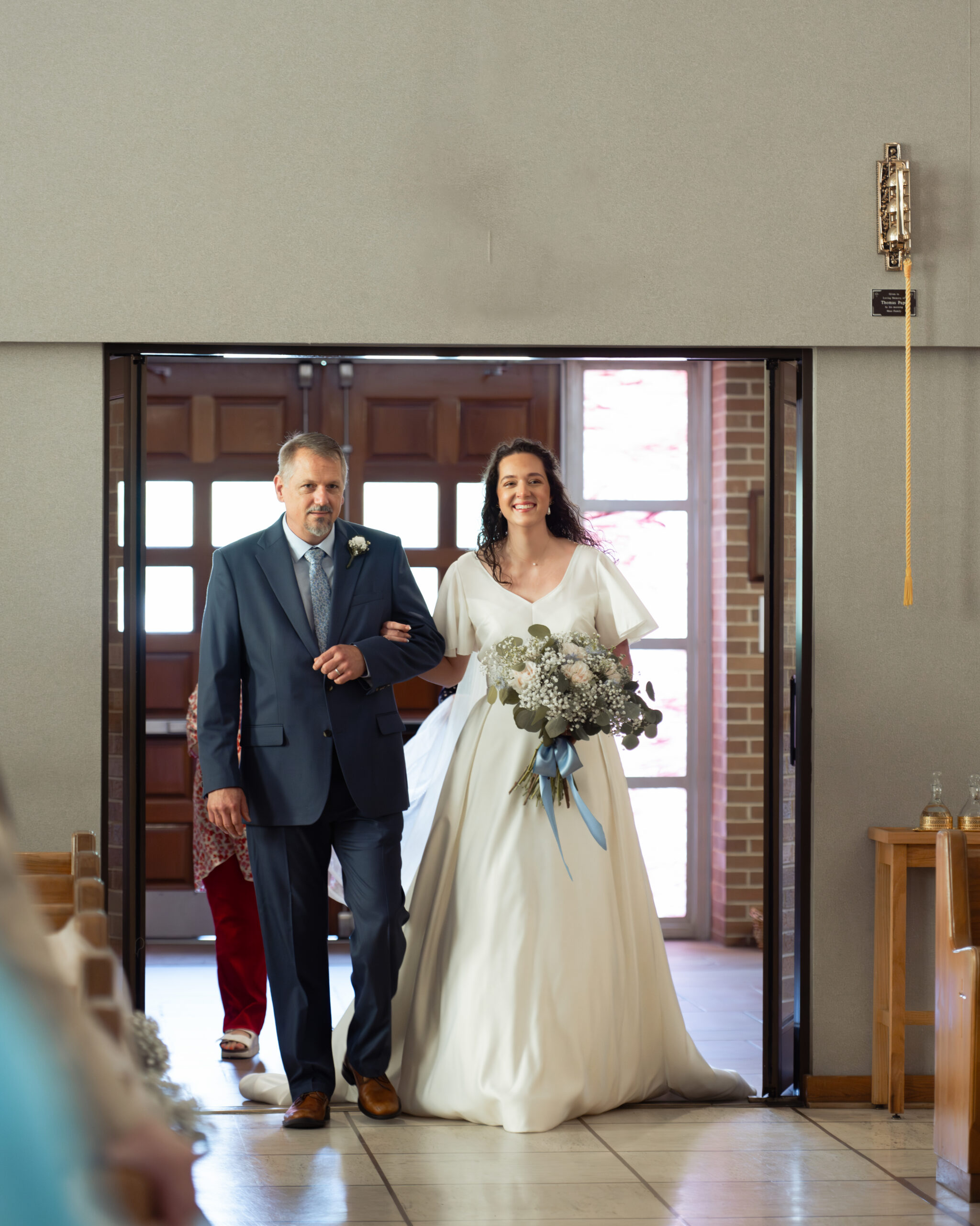 A catholic bride joyfully walks down the aisle with her father during her catholic wedding Mass at Holy Spirit Catholic Church in Huntsville, Alabama