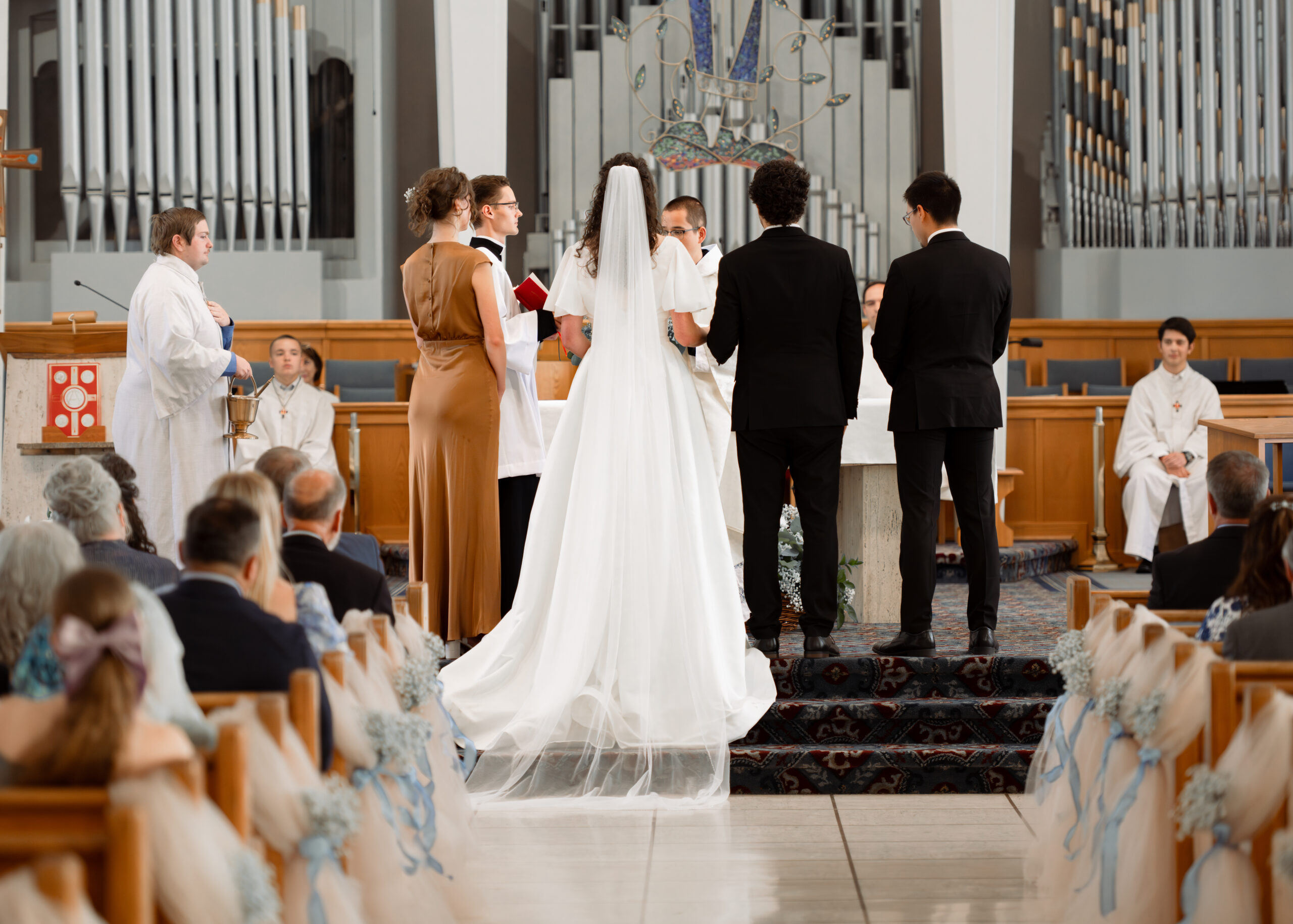 A catholic couple stands at the altar of holy spirit catholic church at the beginning of their catholic wedding Mass in Huntsville, alabama