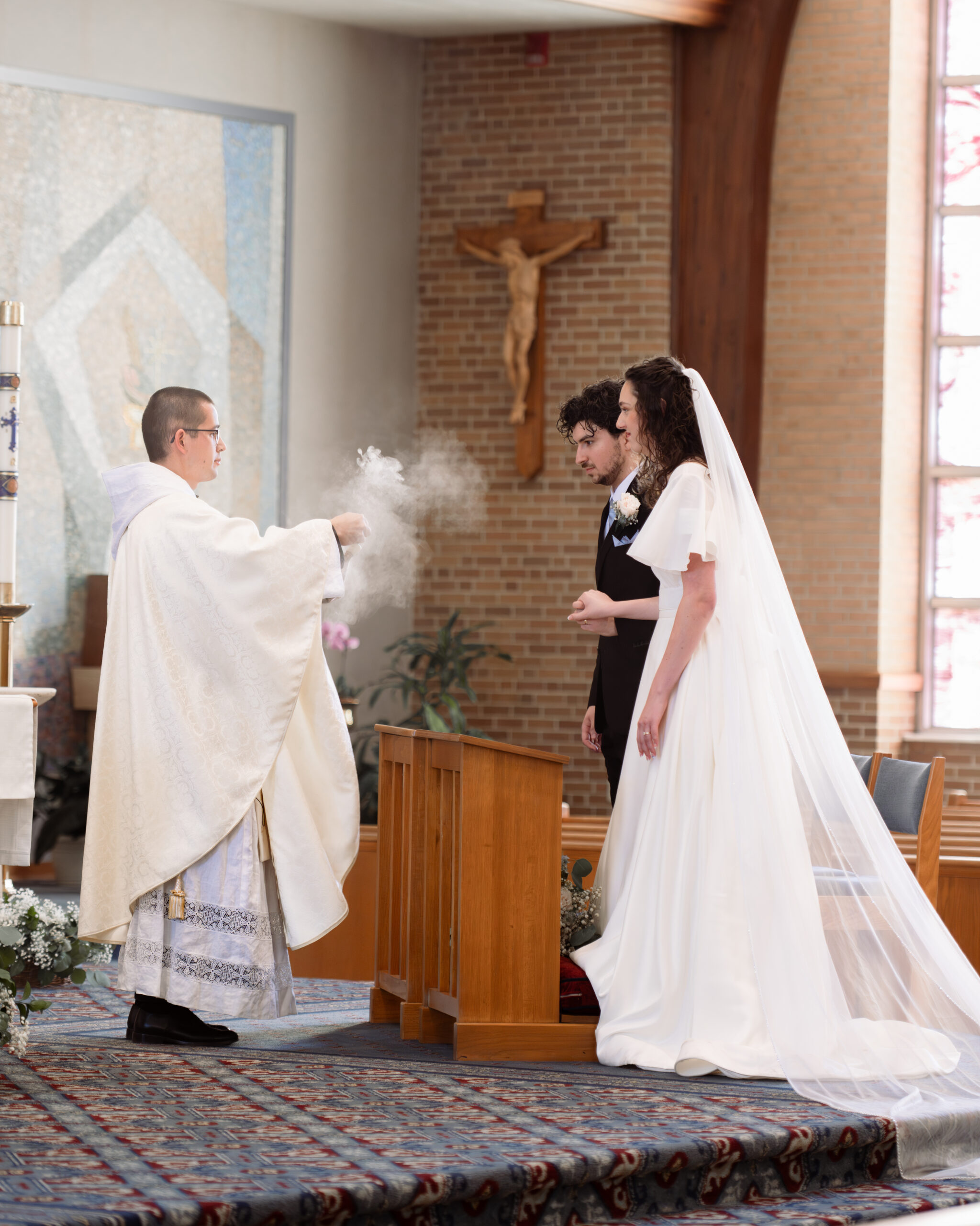 A catholic bride and groom are incensed by the priest during their catholic wedding Mass at holy spirit catholic church in huntsville, alabama
