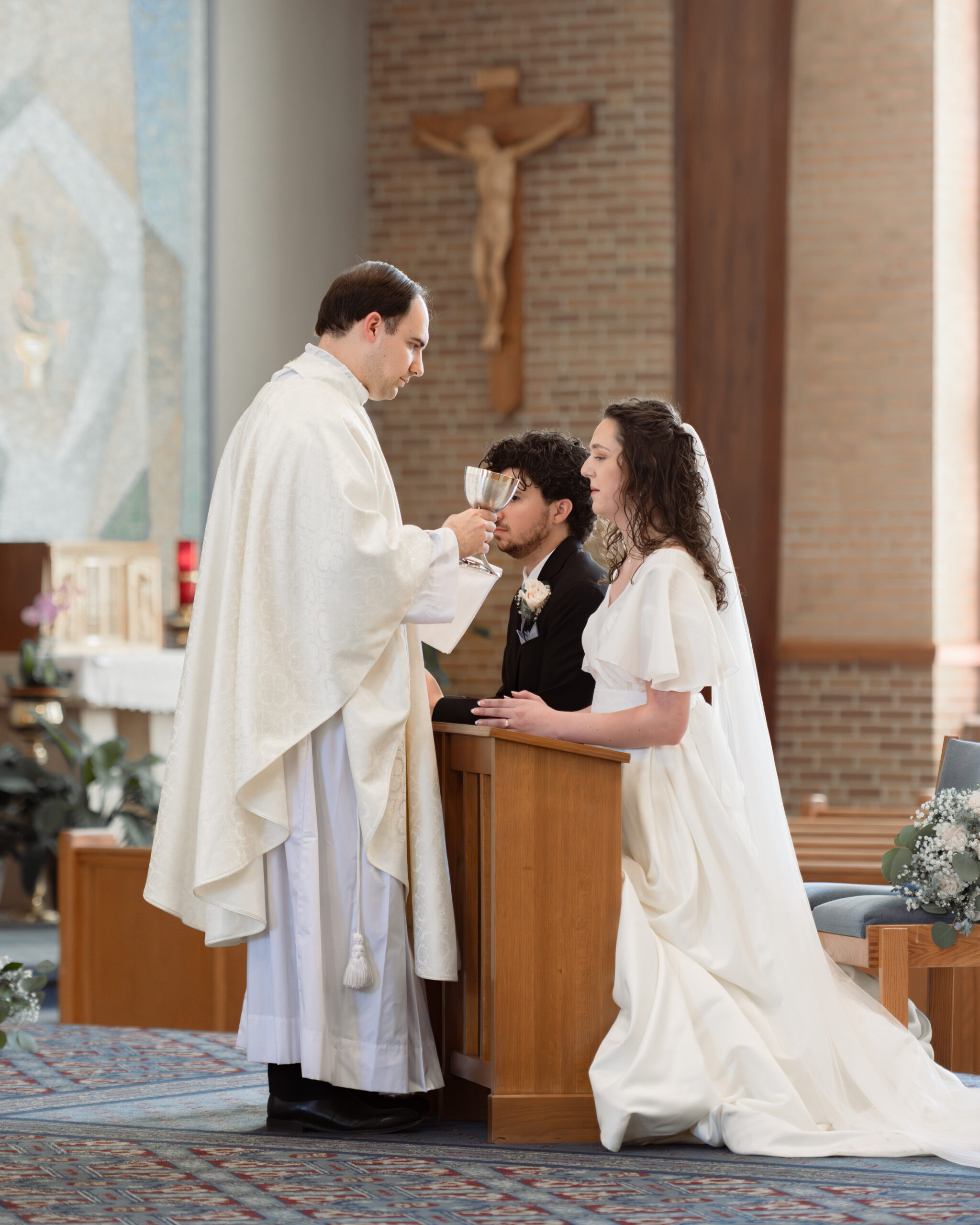 A catholic bride and groom receive holy communion during their catholic wedding Mass at holy spirit catholic church in huntsville, alabama