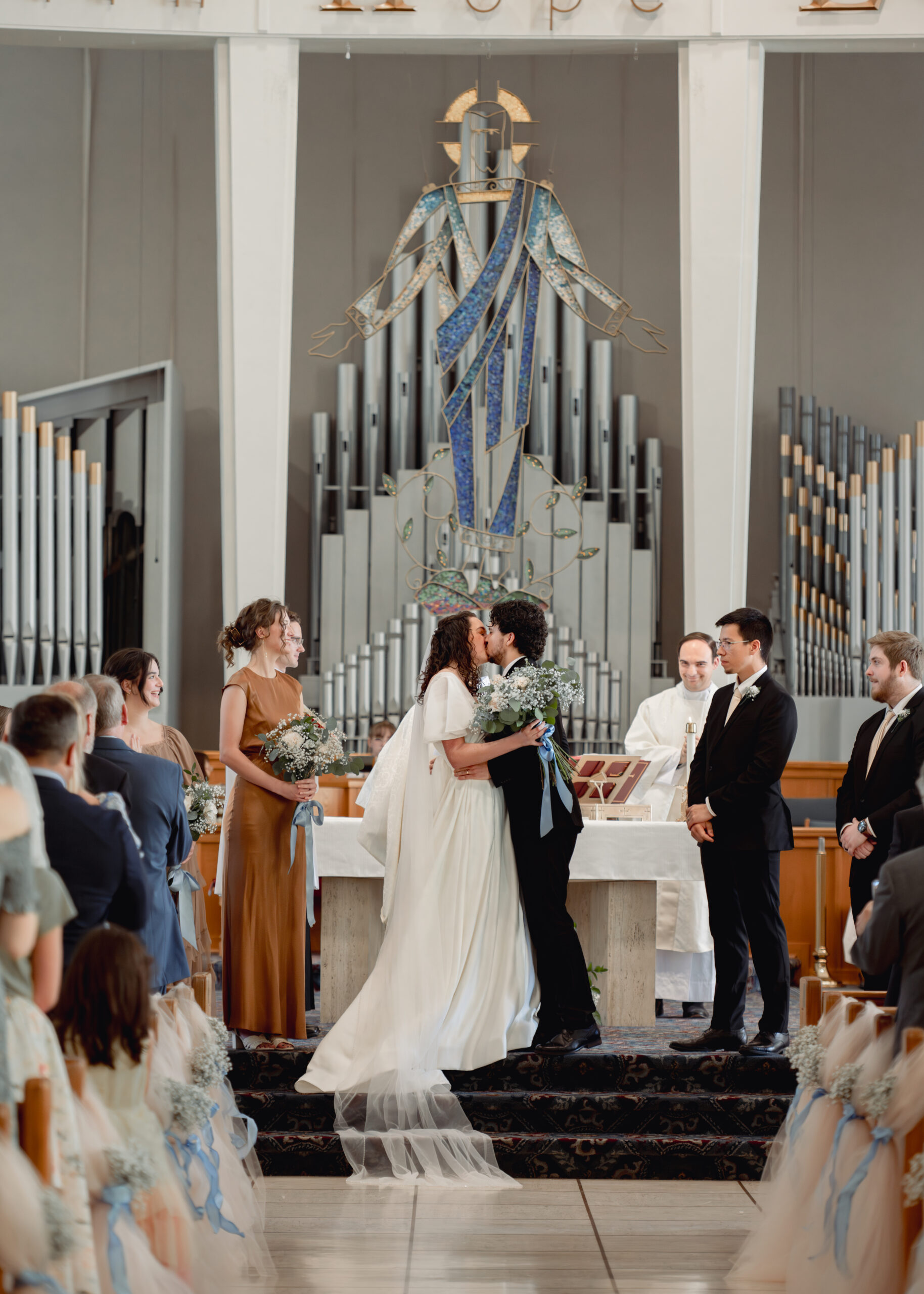A catholic bride and groom share a joyful first kiss at the conclusion of their catholic wedding Mass at holy spirit catholic church in huntsville, alabama