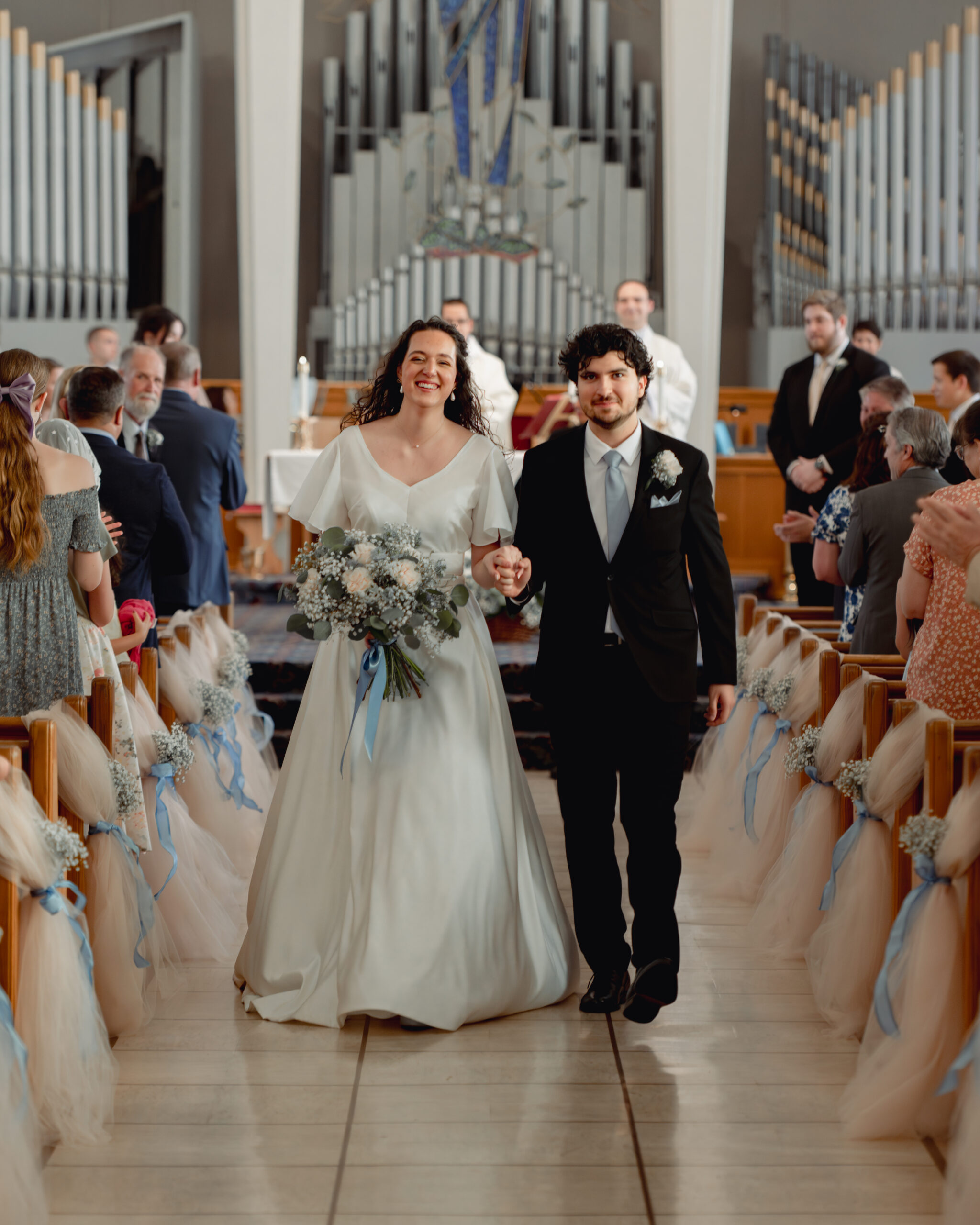A catholic bride and groom joyfully walk down the aisle at the conclusion of their catholic wedding Mass in huntsville, alabama