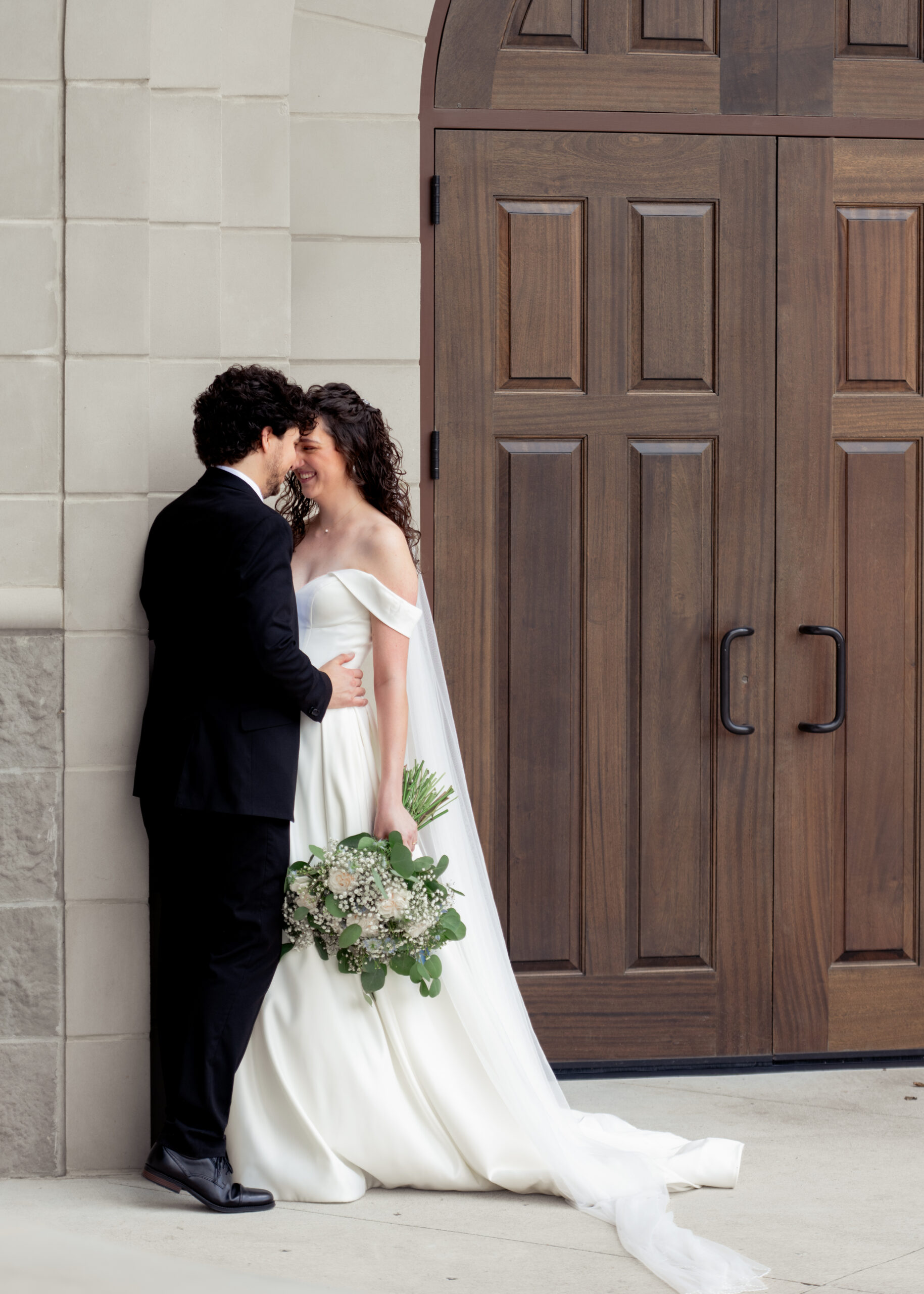 A catholic bride and groom pose for an intimate and romatic portrait outside the chapel of Holy Spirit catholic church in Huntsville, Alabama