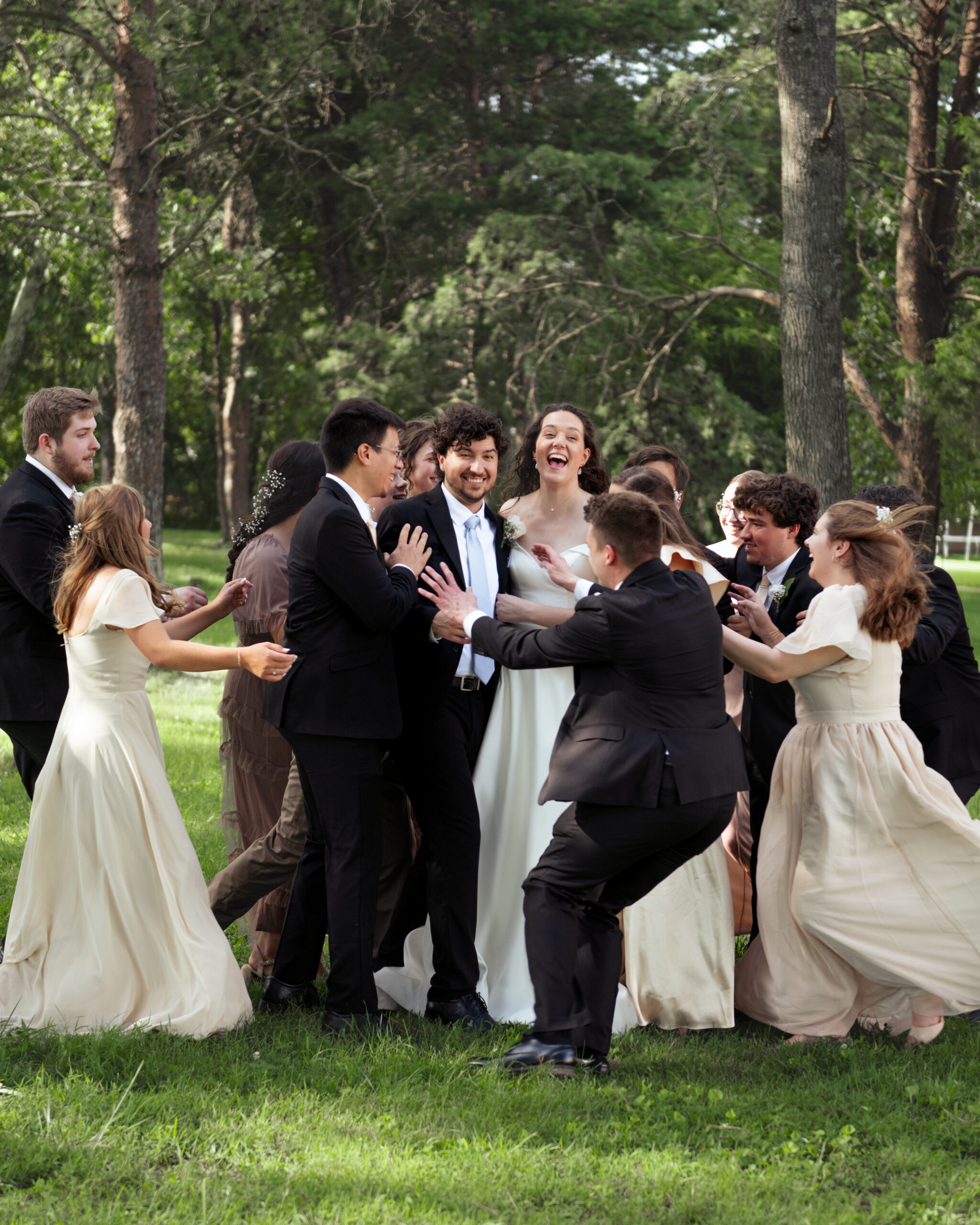 A wedding party runs to embrace a newly married catholic couple during group photos outside of a wedding reception venue in athens, alabama