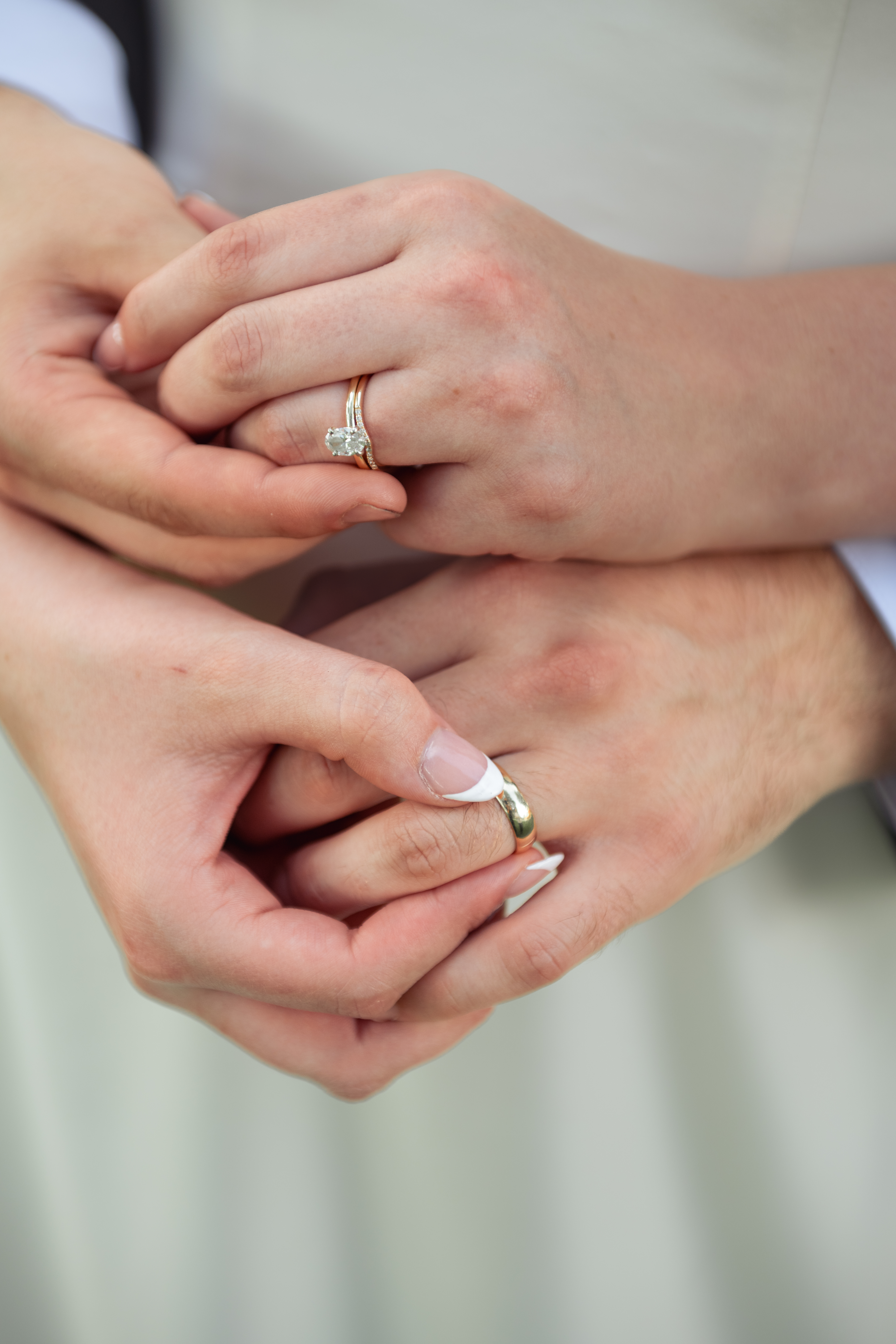 A detail photograph of a newly married couple's hands adjusting each other's new wedding bands.