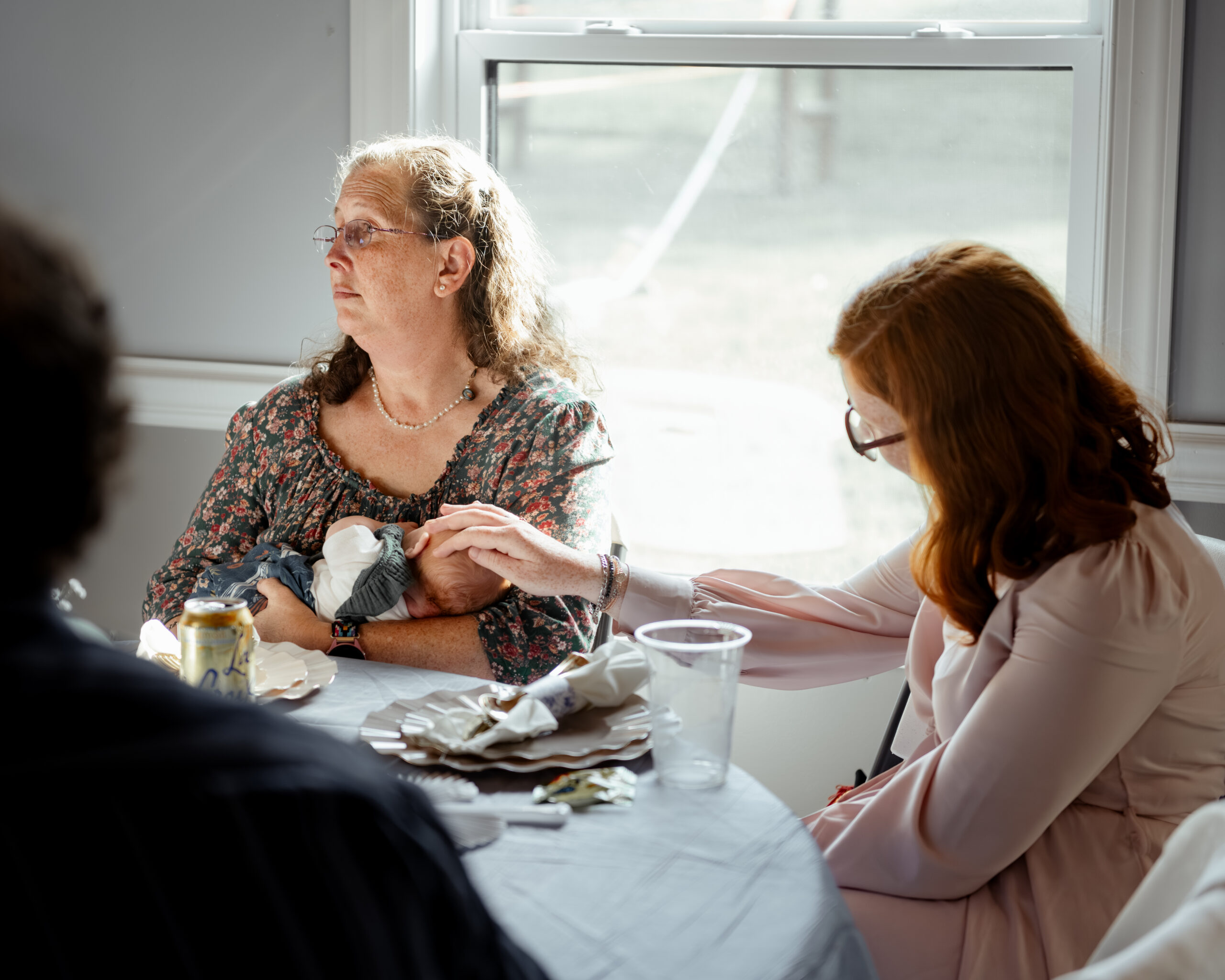 wedding guests interact with each other near a bright sunny window at southern charm in athens alabama during a large catholic wedding reception
