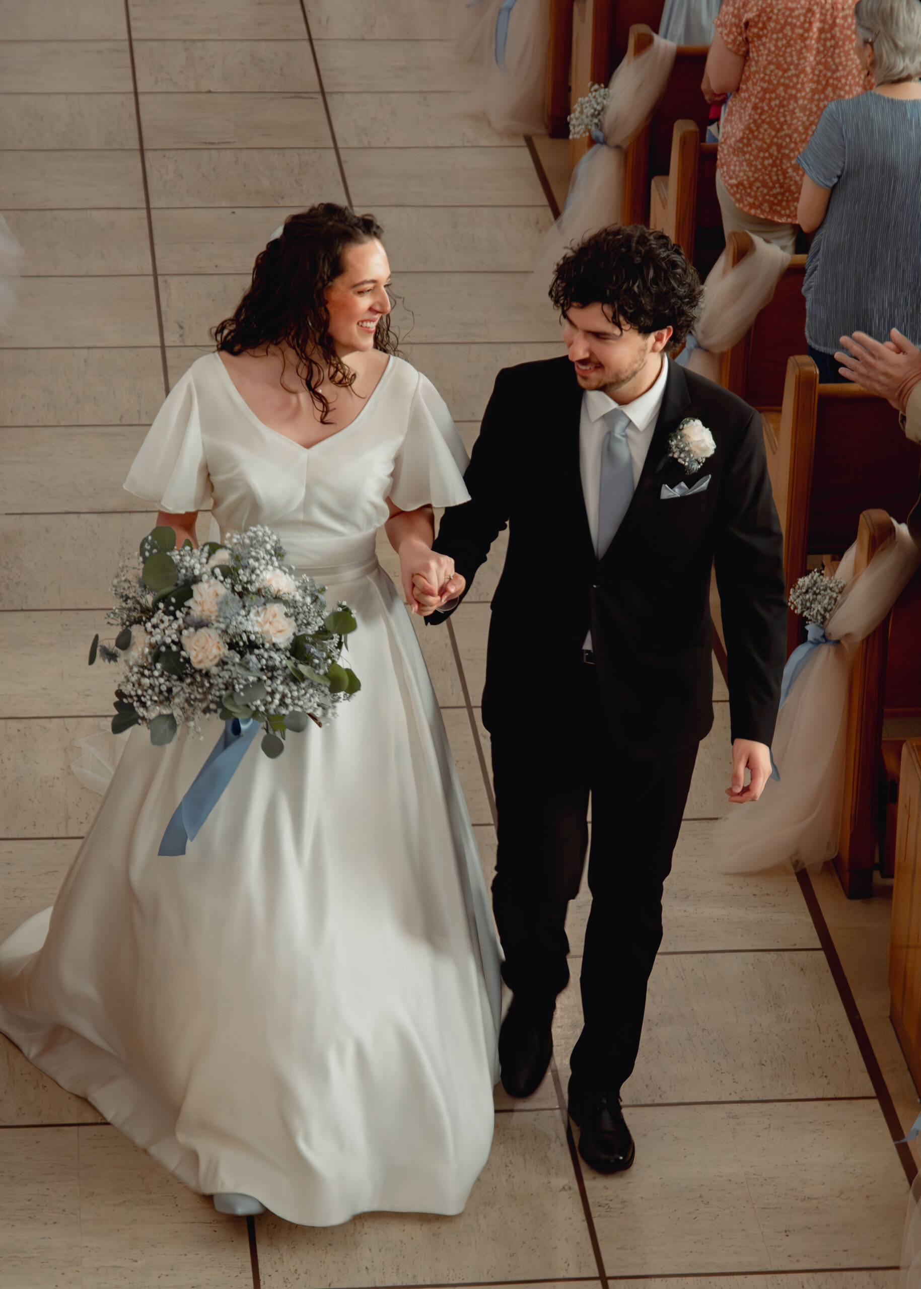 A catholic bride and groom joyfully walk down the aisle at the conclusion of their catholic wedding Mass in huntsville, alabama. This angle was taken from above in a choir loft