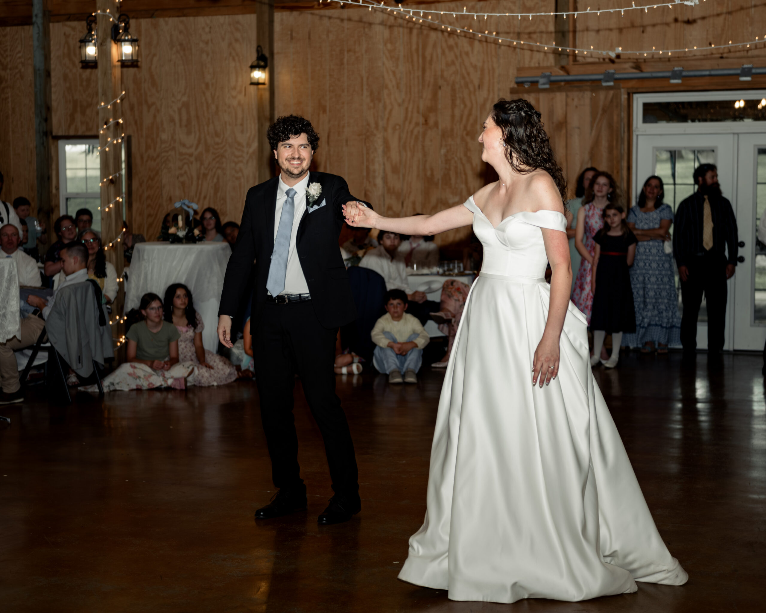 The bride and groom smile at each other as the prepare for their first dance at a large catholic wedding reception at southern charm in athens, alabama