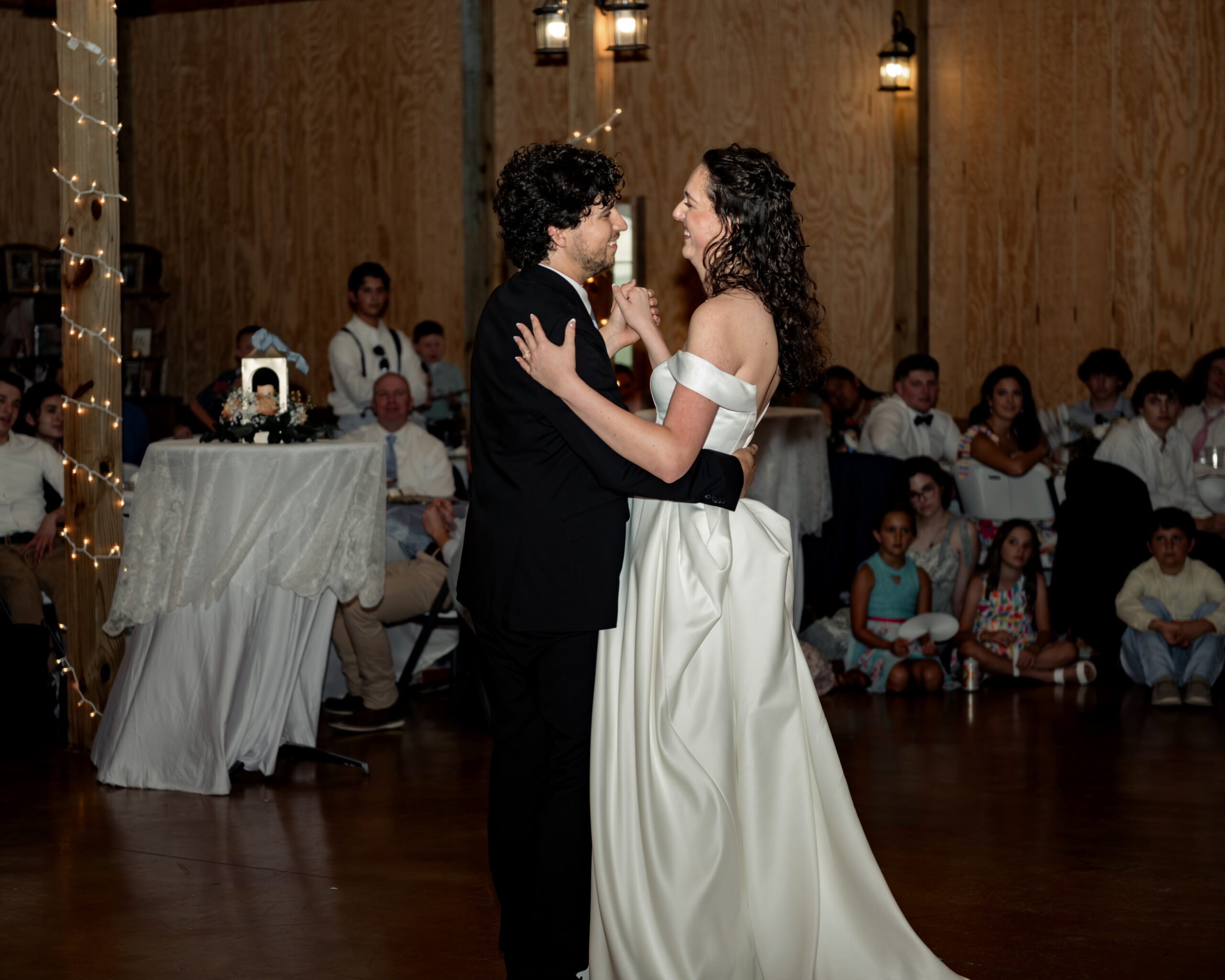 The bride and groom laugh with each other during their first dance at a large catholic wedding reception at southern charm in athens, alabama