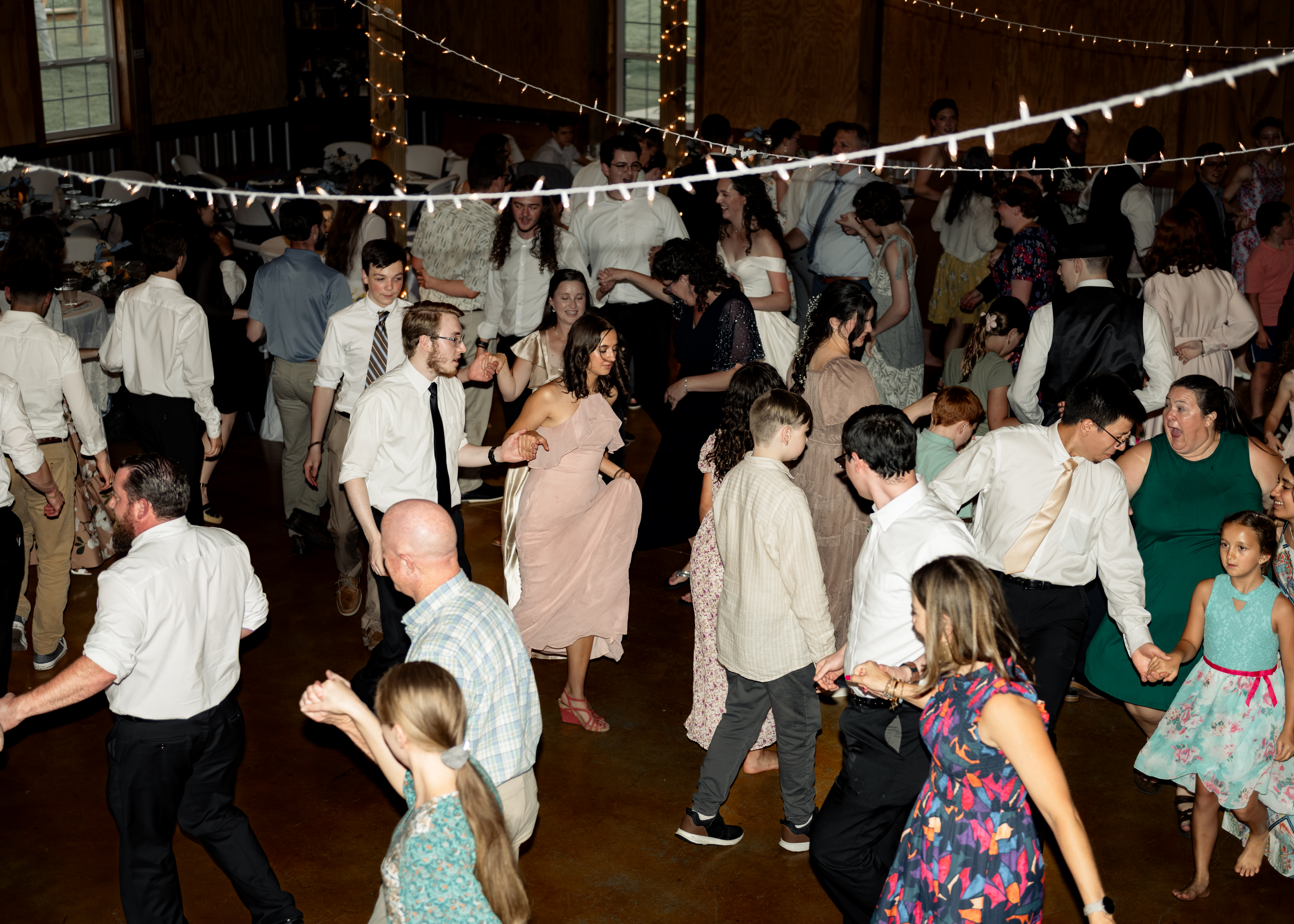 Guests enthusiastically dance a traditional line dance at a large catholic wedding reception at southern charm in athens, alabama