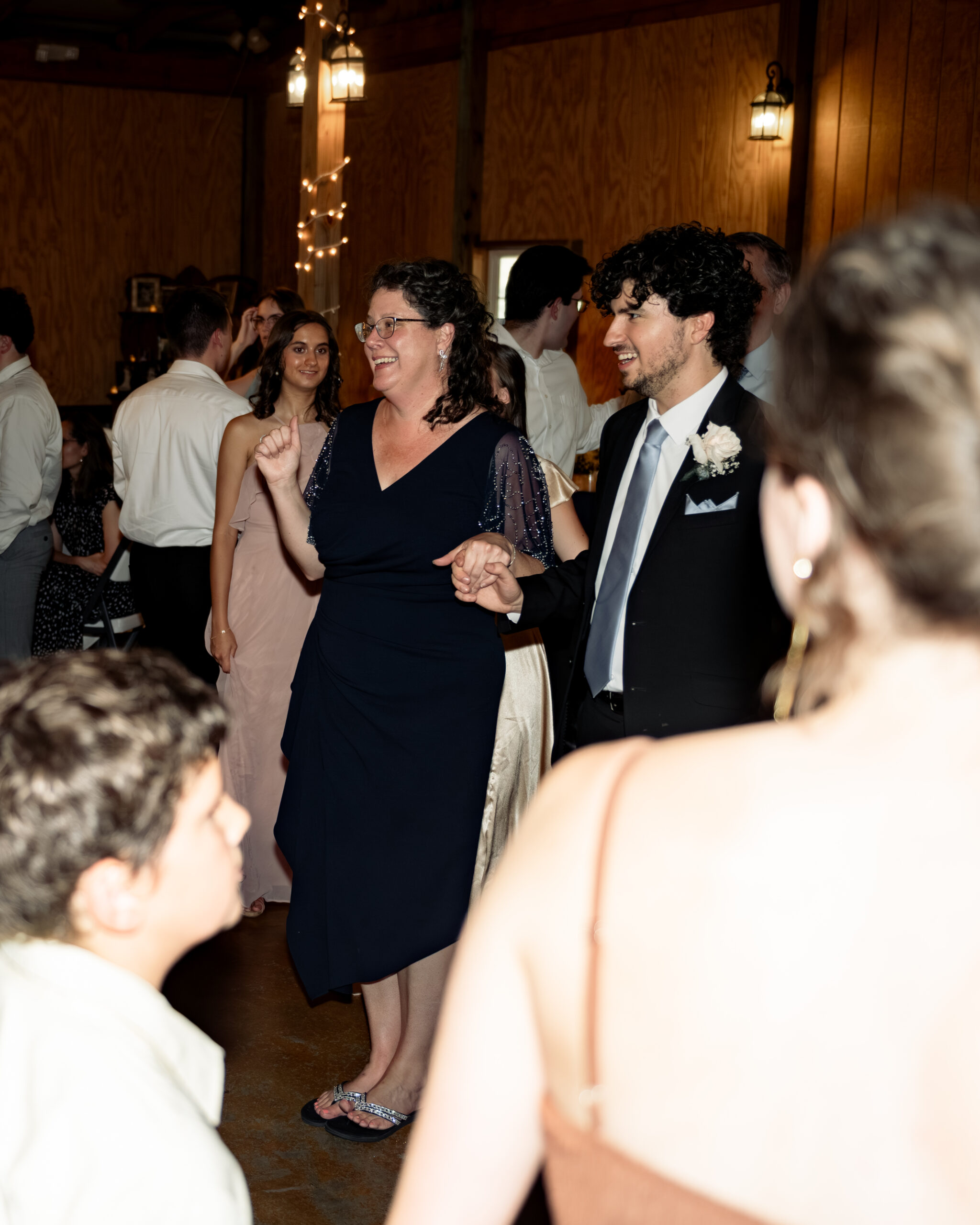 The bride's mother dances with the groom during a traditional line dance at a large catholic wedding reception at southern charm in athens, alabama