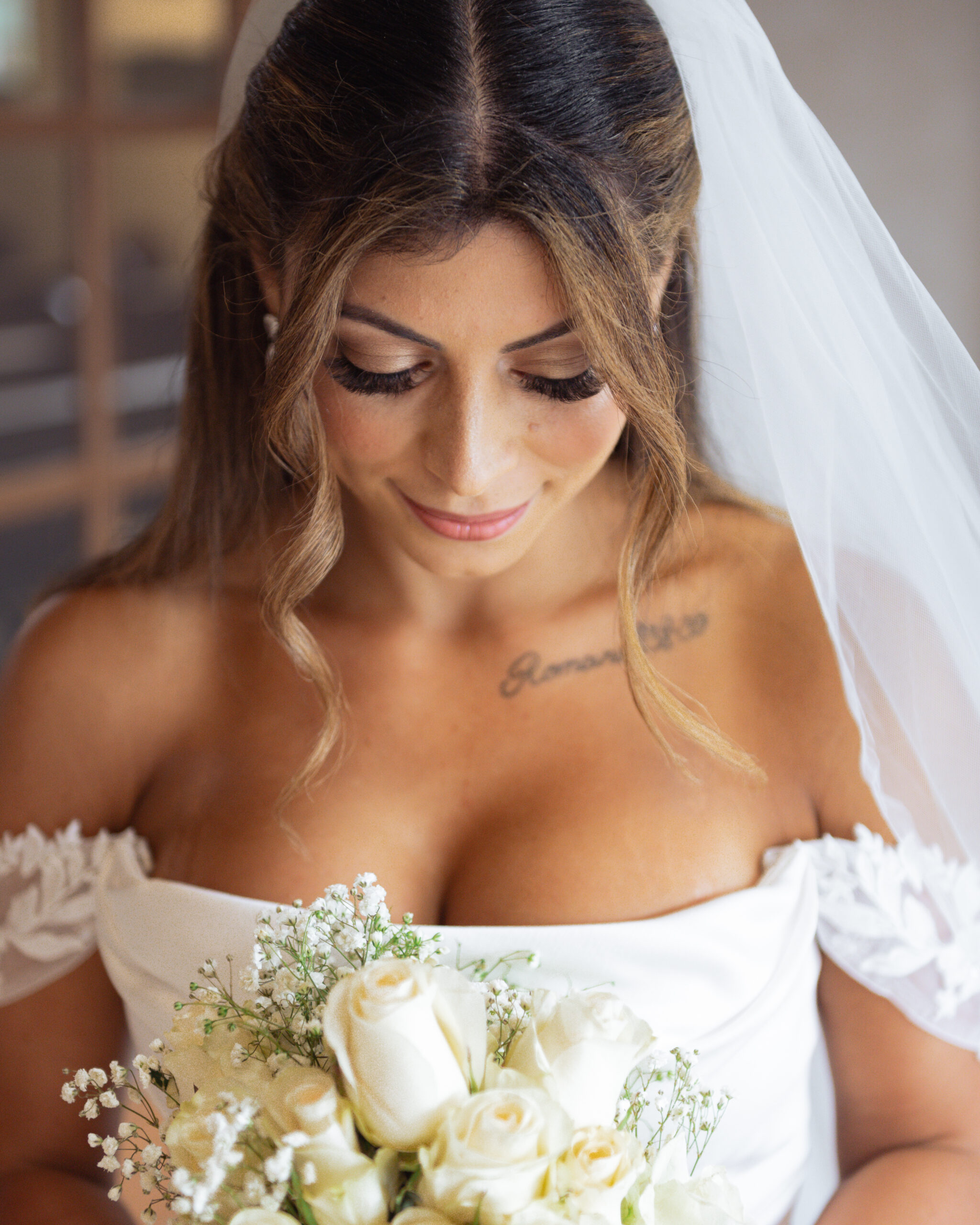 A close up portrait of a catholic bride shows her stunning white bouquet at St. Ann's Catholic Church in Nashville, TN