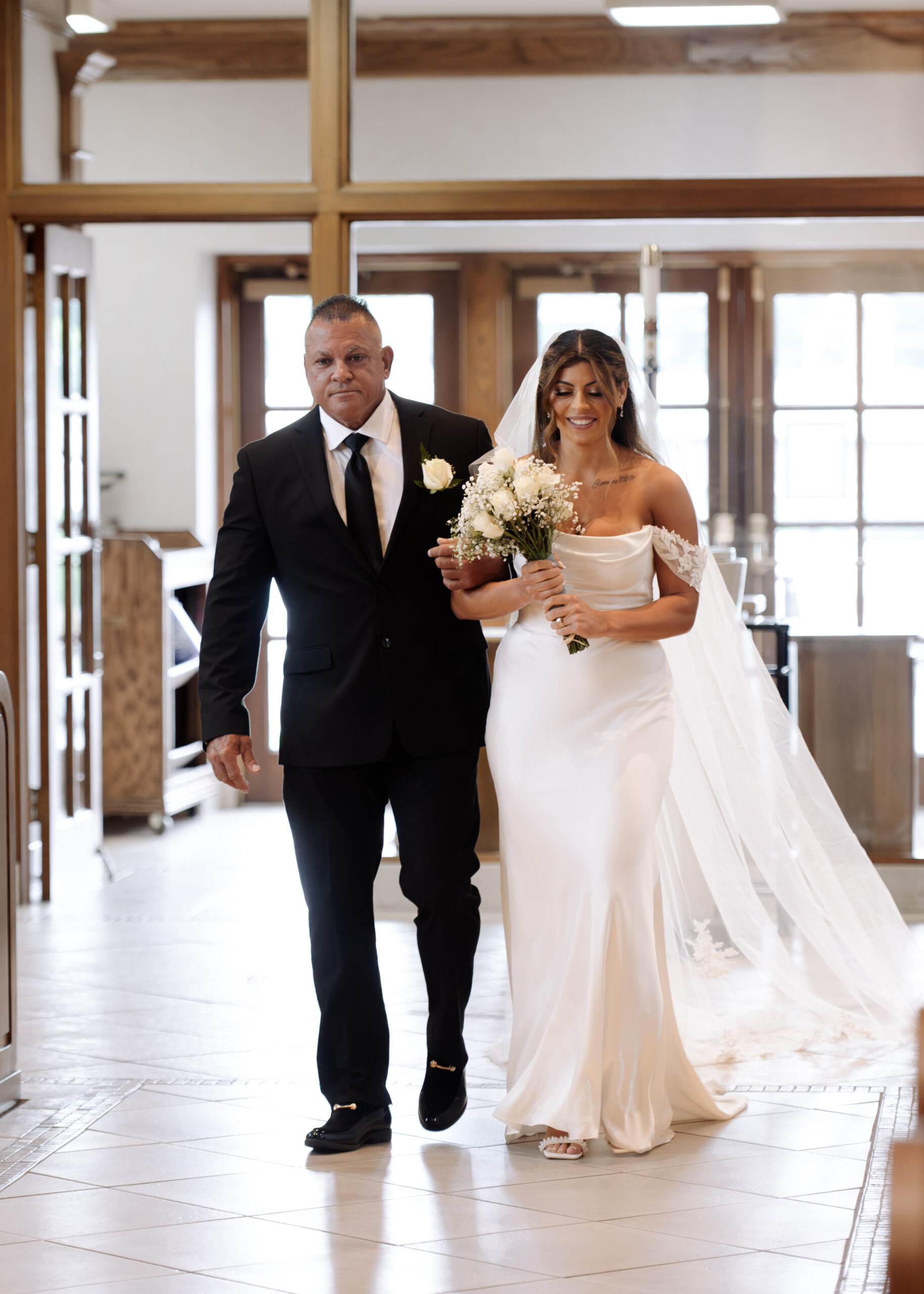 A catholic bride and her father walk down the aisle during a catholic wedding ceremony at St. Ann's Catholic Church in Nashville, TN