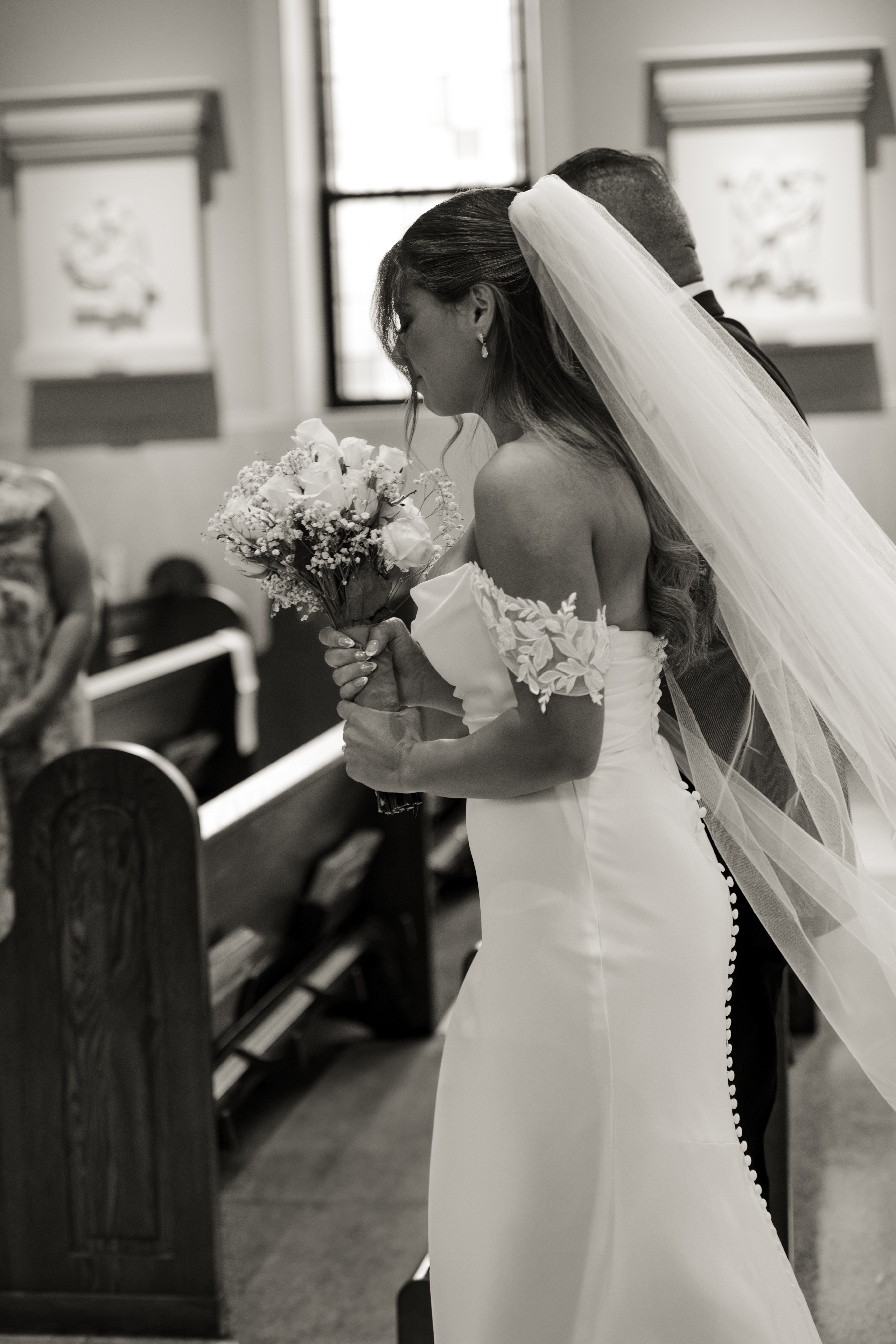 A black and white action portrait of a catholic bride walking down the aisle during a catholic wedding ceremony at St. Ann's Catholic Church in Nashville, TN