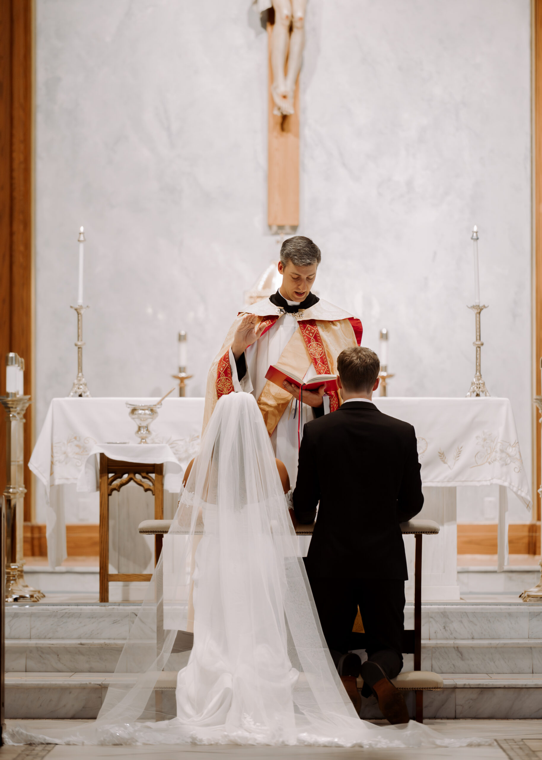The presiding deacon blesses the bride and groom at the end of a catholic wedding ceremony at St. Ann's Catholic Church in Nashville, TN