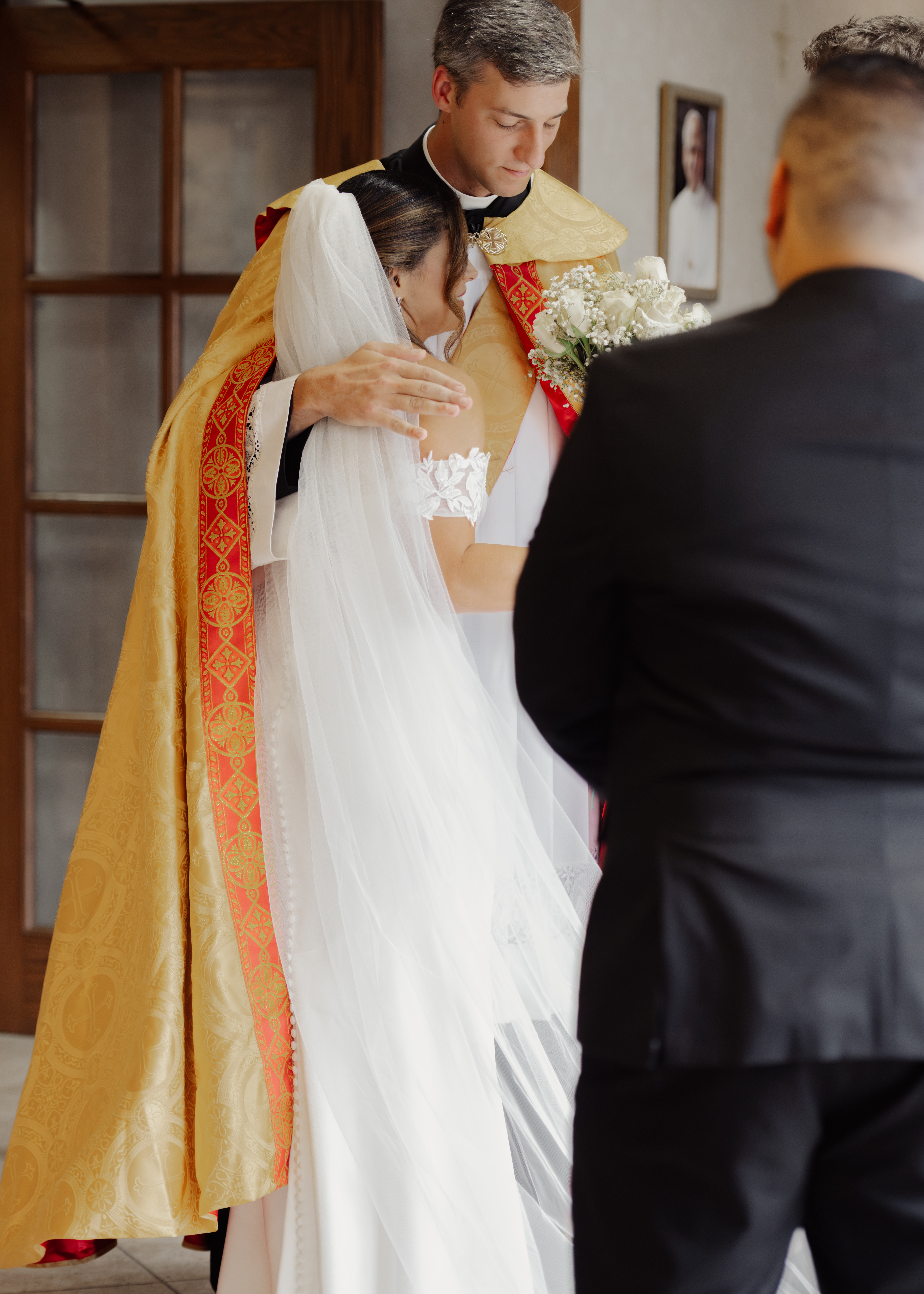 A deacon hugs the bride after a catholic wedding ceremony at St. Ann's Catholic Church in Nashville, TN