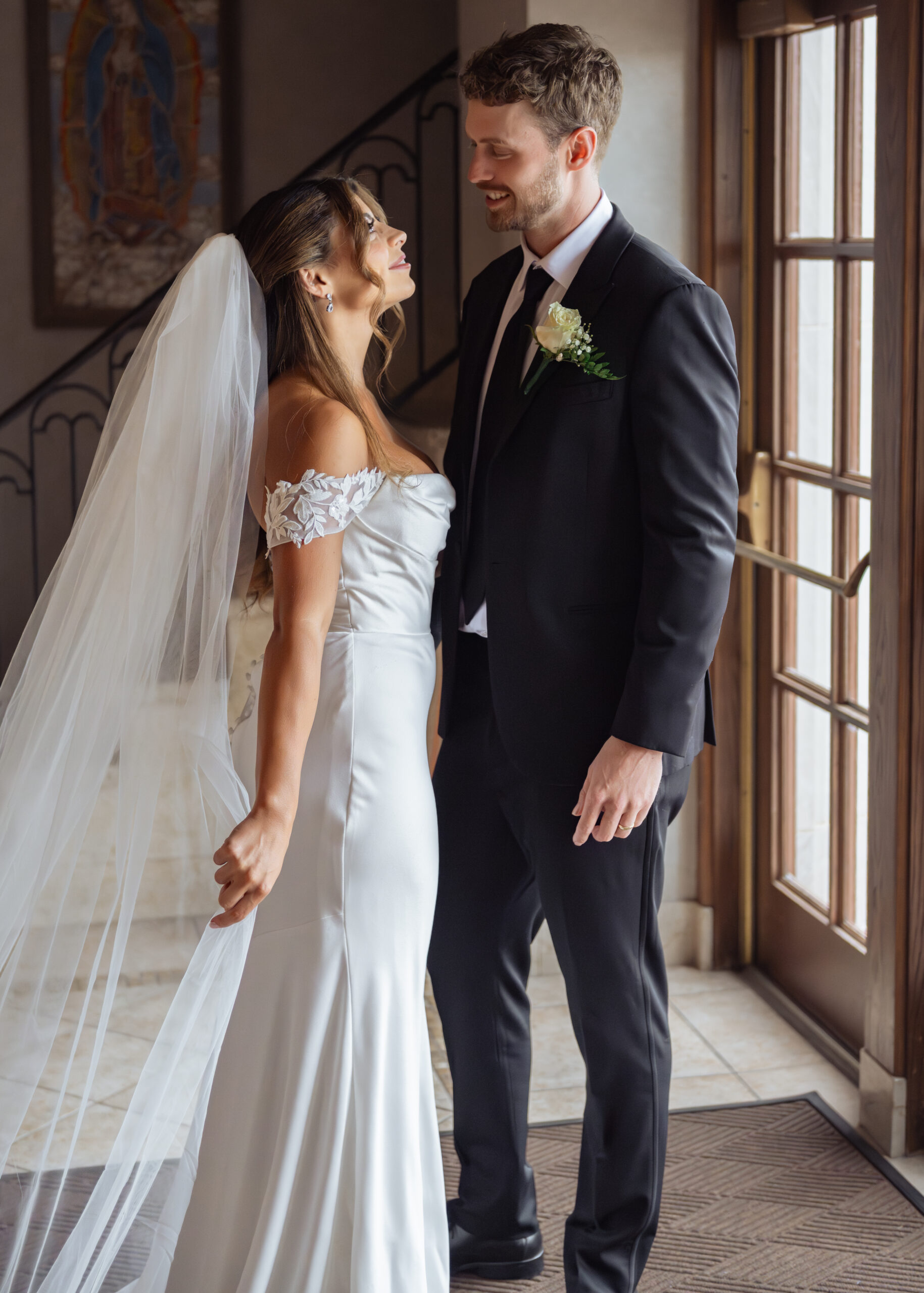 A catholic bride and groom stare lovingly into each others eyes and laugh during a relaxed portrait after their Catholic wedding ceremony at St. Ann's Catholic Church in downtown Nashville.