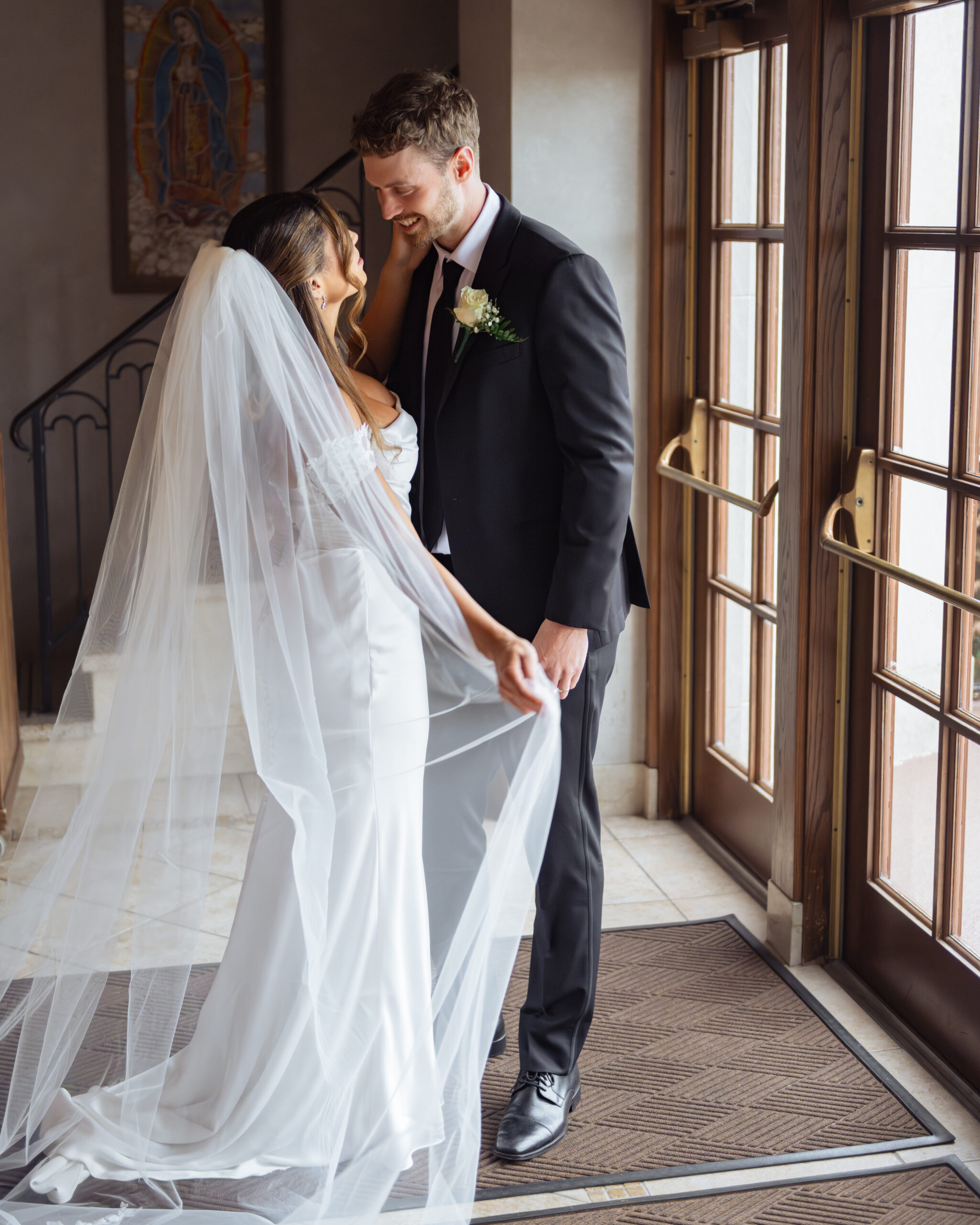 A catholic bride and groom pose for a portrait in front of a portrait of Mary after their Catholic wedding ceremony at St. Ann's Catholic Church in downtown Nashville.