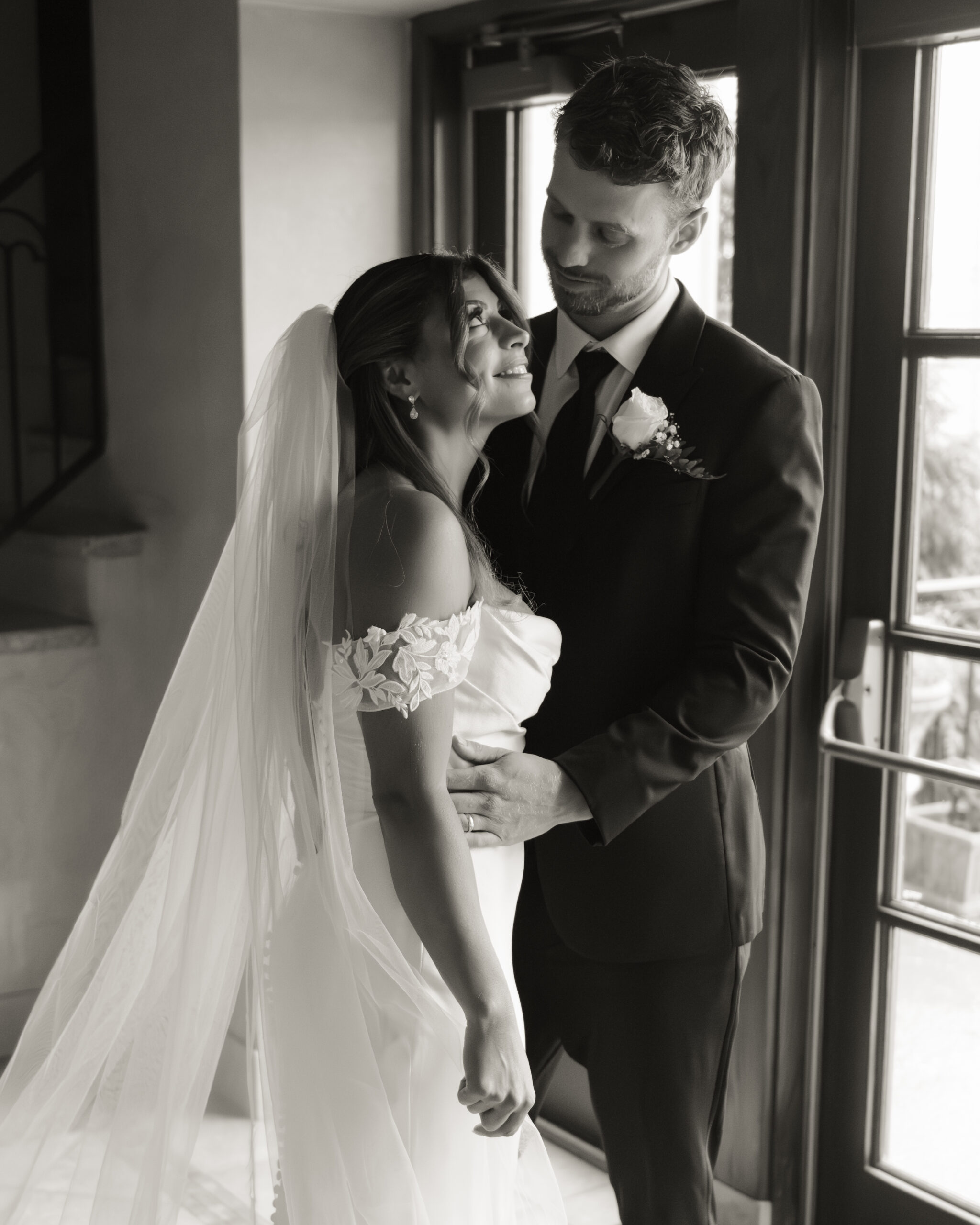 A catholic bride and groom look at each other during this simple black and white wedding portrait in dreamy light after their Catholic wedding ceremony at St. Ann's Catholic Church in downtown Nashville.