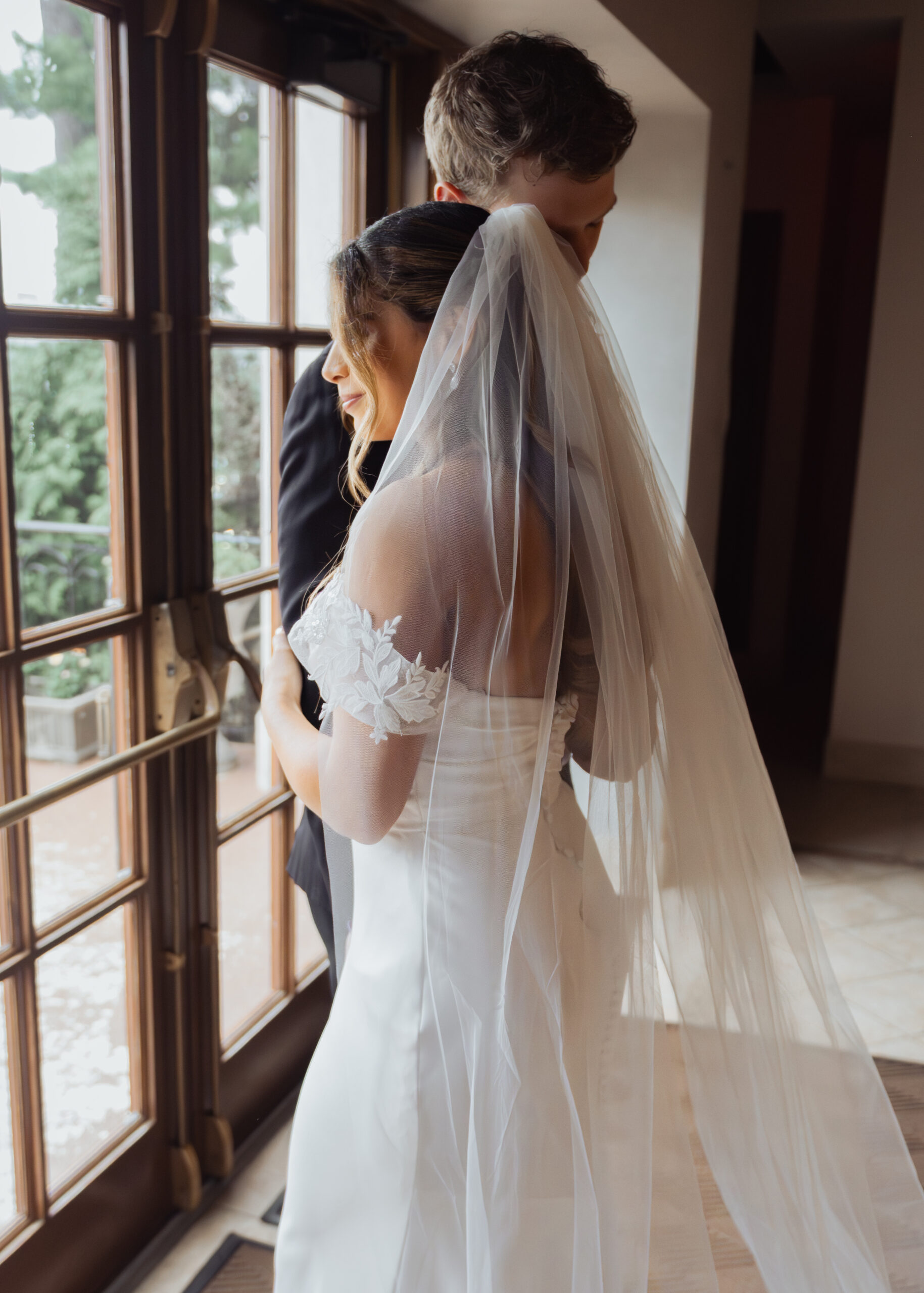 A catholic bride and groom share an intimate moment in front of a rainy window after their Catholic wedding ceremony at St. Ann's Catholic Church in downtown Nashville.