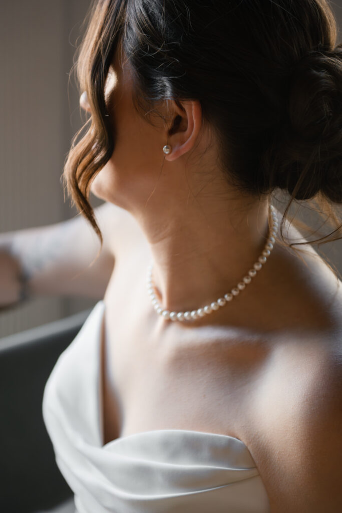 a louisville catholic bride poses for an elegant detail photograph of her classic jewelry ahead of her catholic wedding at st. boniface in louisville, ky