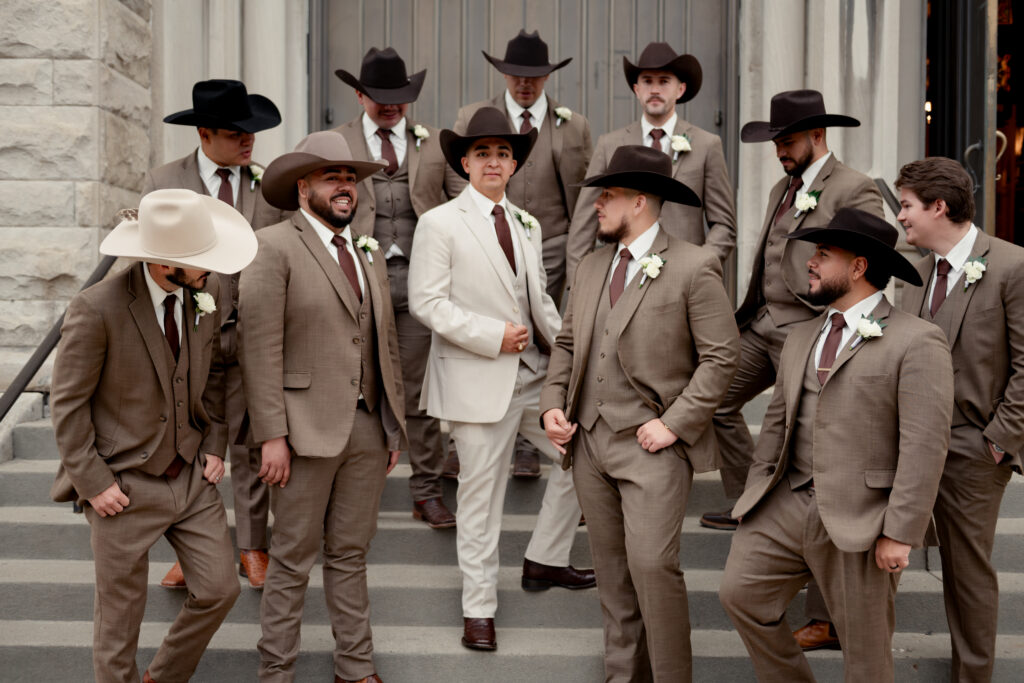 catholic groomsmen and groom pose in front of st. boniface catholic church in downtown louisville kentucky after a traditional catholic wedding mass